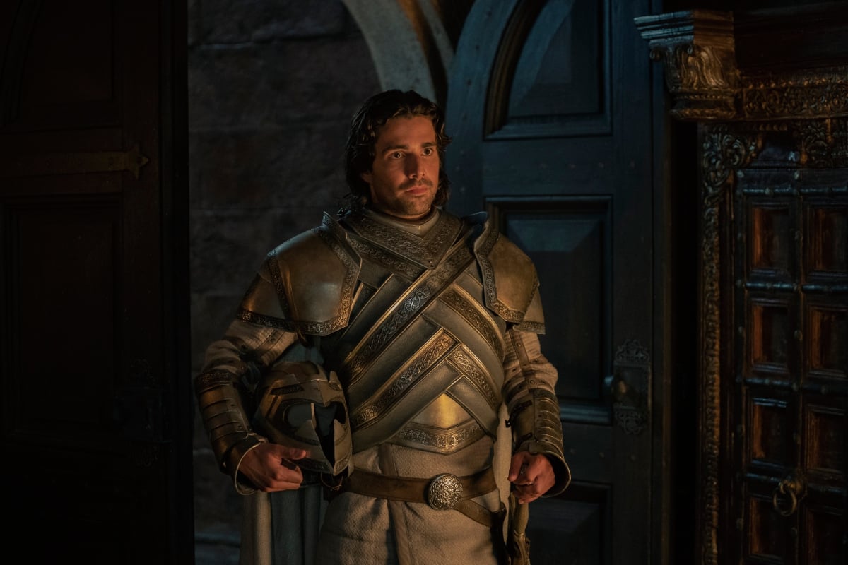 Fabien Frankel as Ser Criston Cole in House of the Dragon. Criston wears a suit of armor and carries his helmet under his arm. 