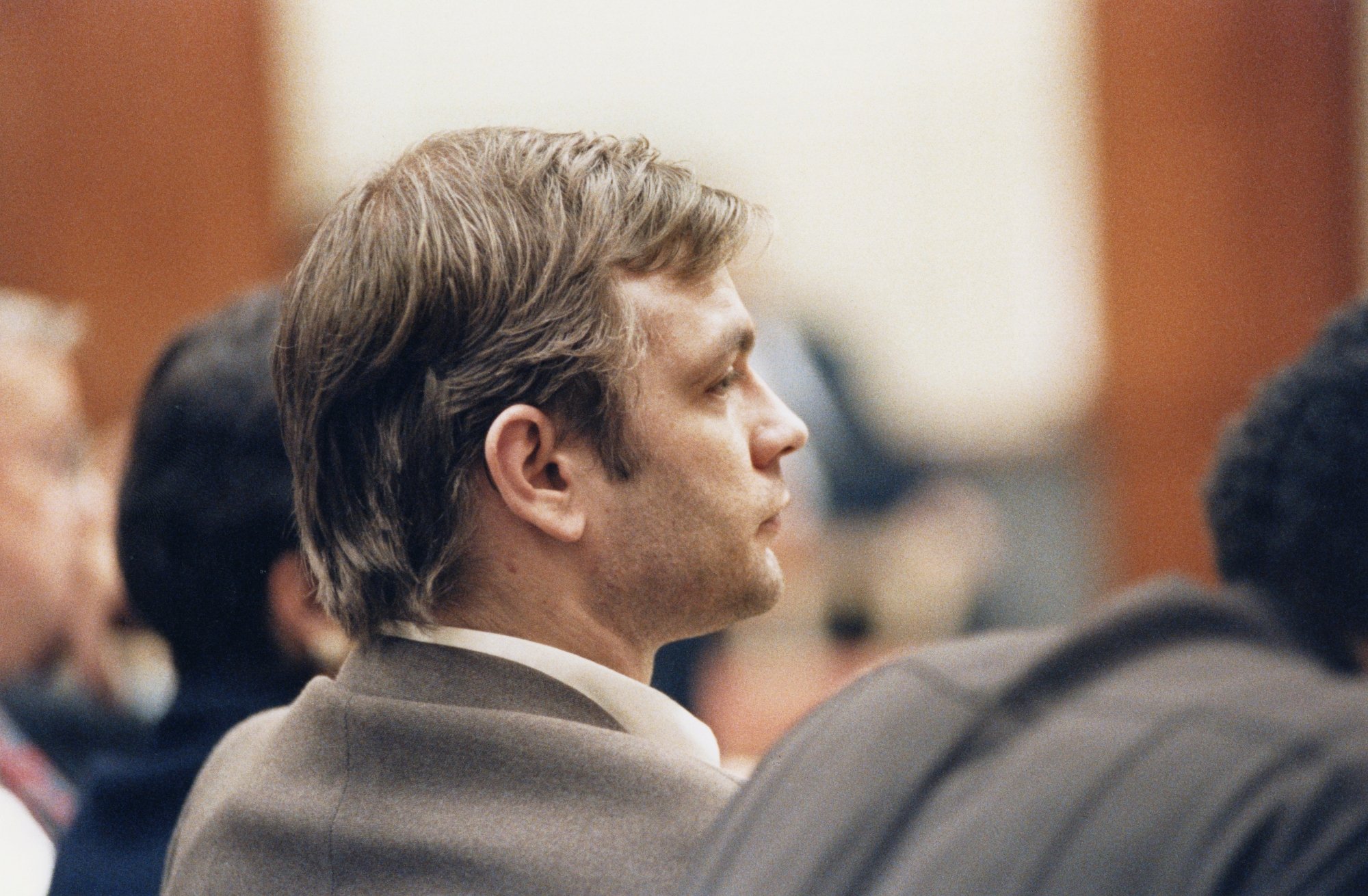 Jeffrey Dahmer, whose victims' families argued over auction of his property. He's wearing a grey suit jacket and looking ahead away from the camera at his trial in a courtroom.