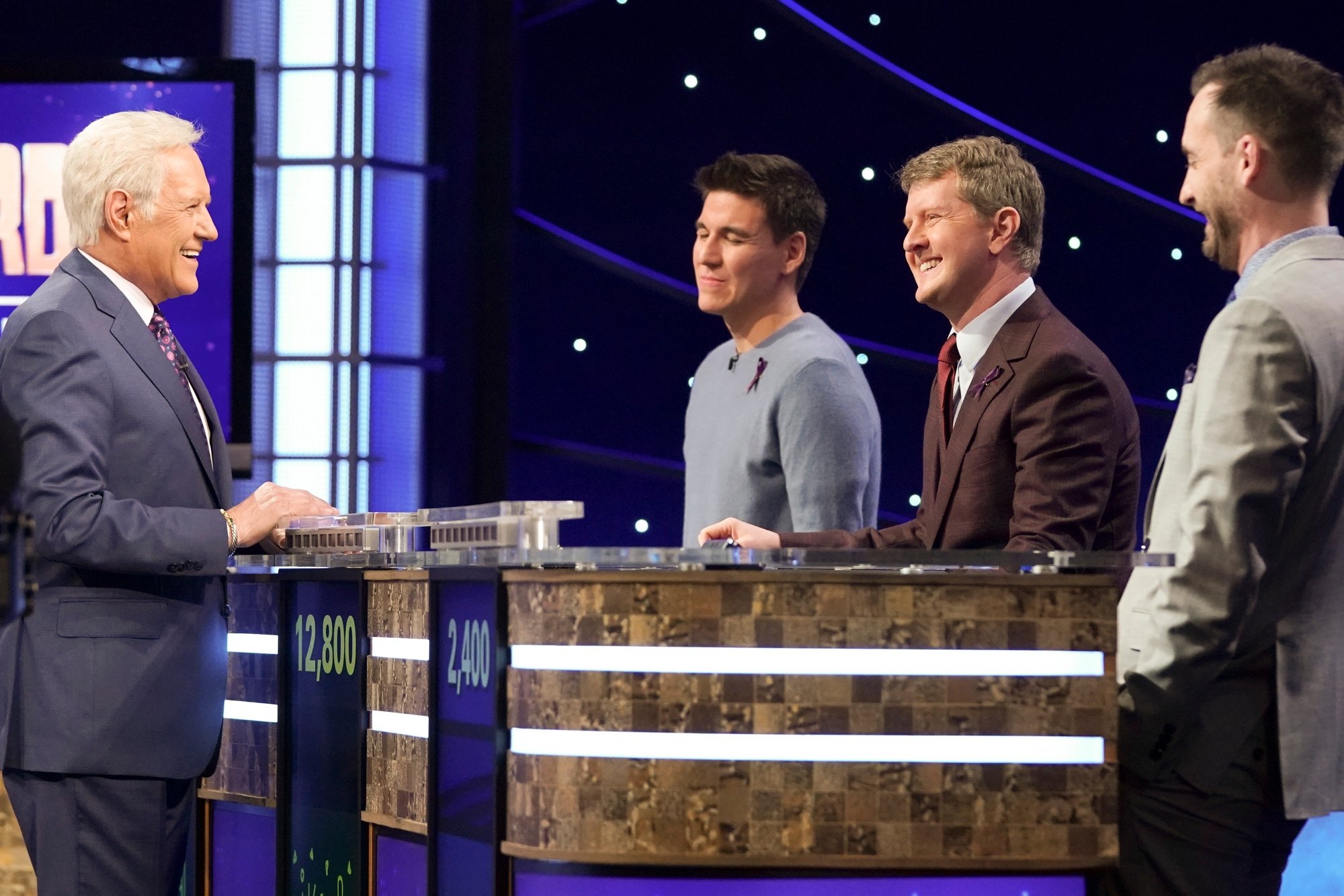 'Jeopardy!' Alex Trebek, James Holzhauer, Ken Jennings, and Brad Rutter in preparation smiling dressed in formal clothes with contestant podiums in between them