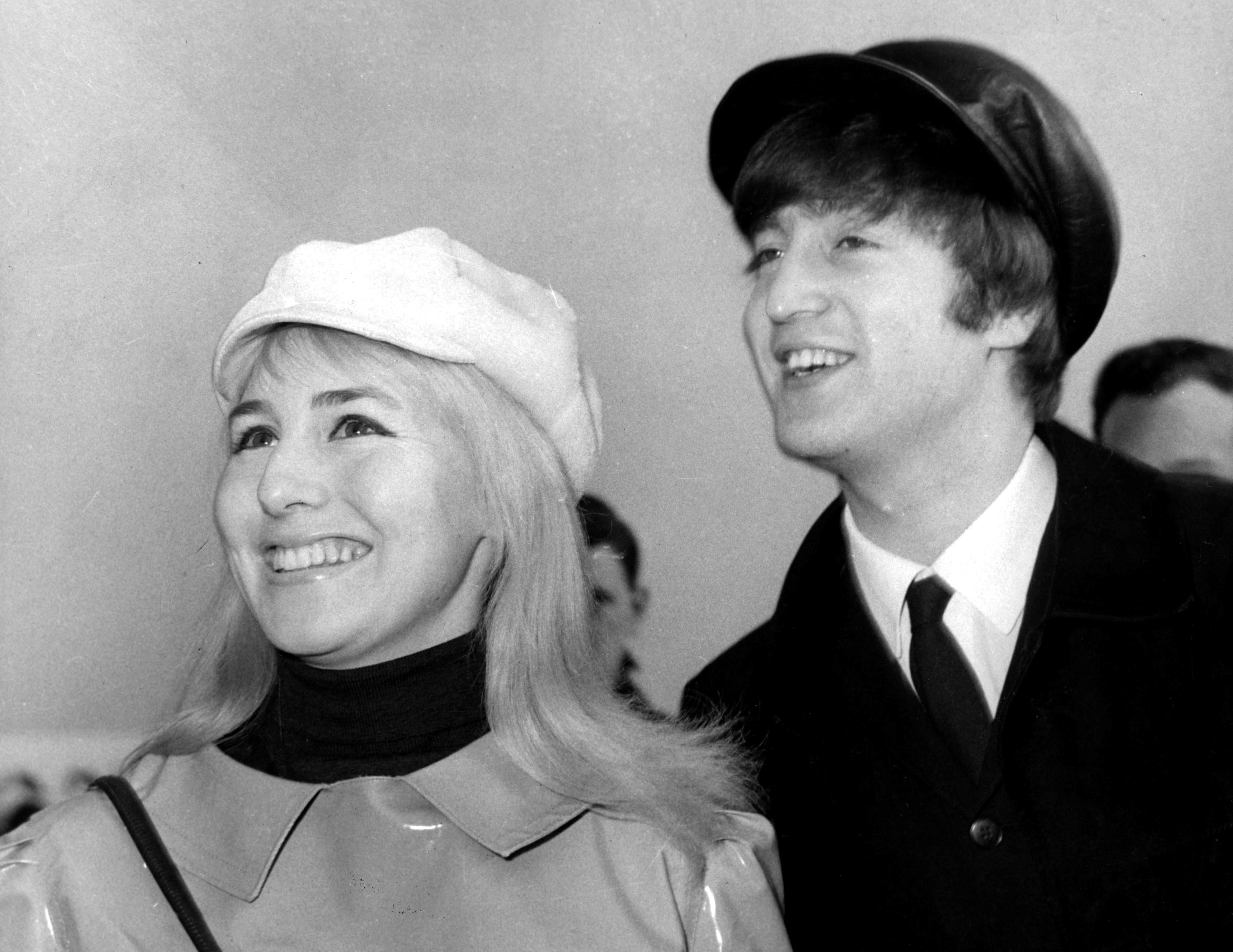 A black and white picture of Cynthia Lennon and John Lennon wearing hats.