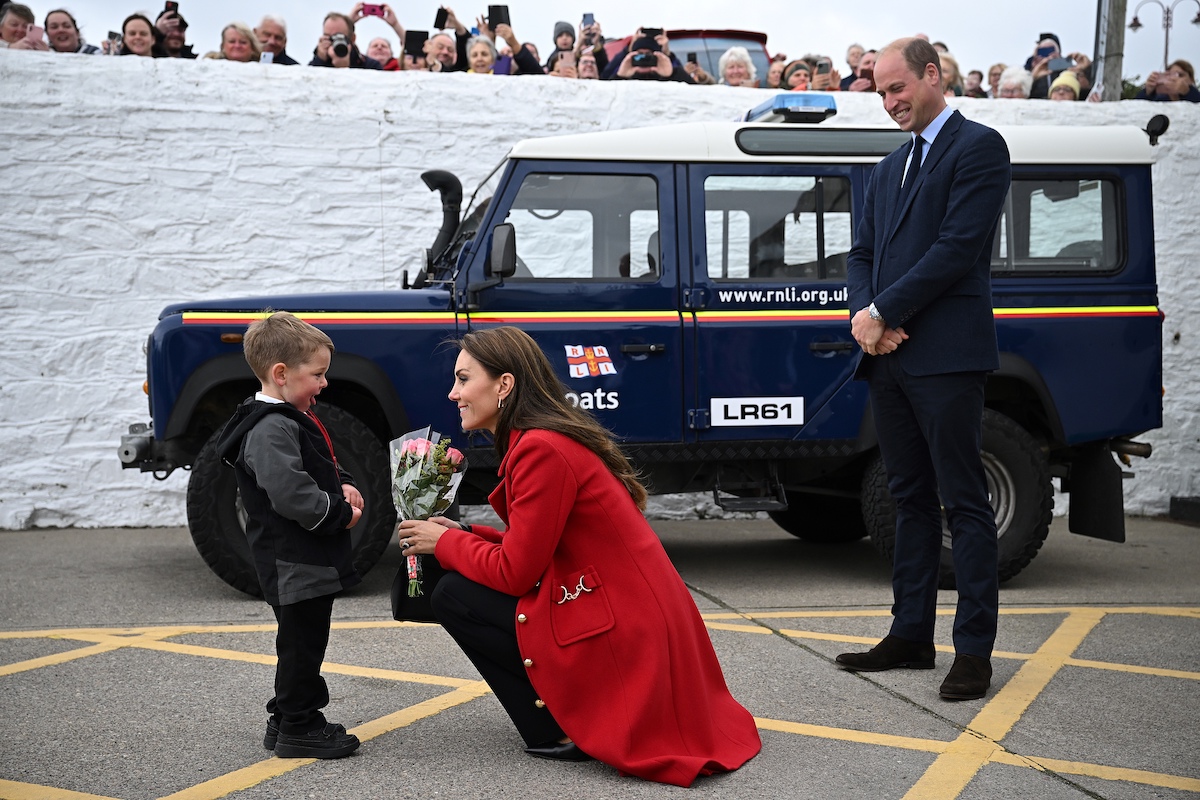 Theo Crompton talks to Kate Middleton, who according to body language expert Judi James says demonstrated the boy had her 'total attention' when she didn't care about her coat touching the ground, takes flowers as Prince William looks on during a visit to Wales on Sept. 27. 2022