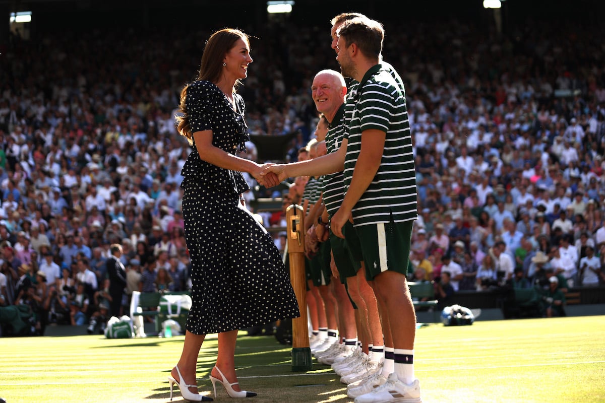 Kate Middleton wears a polka dot dress in her signature Kate Middleton style as she shakes hands with staff at Wimbledon 2022