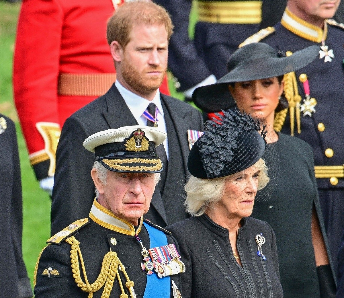 King Charles III, Camilla Parker Bowles, Prince Harry, and Meghan Markle watch as Queen Elizabeth II's coffin arrives at Wellington Arch