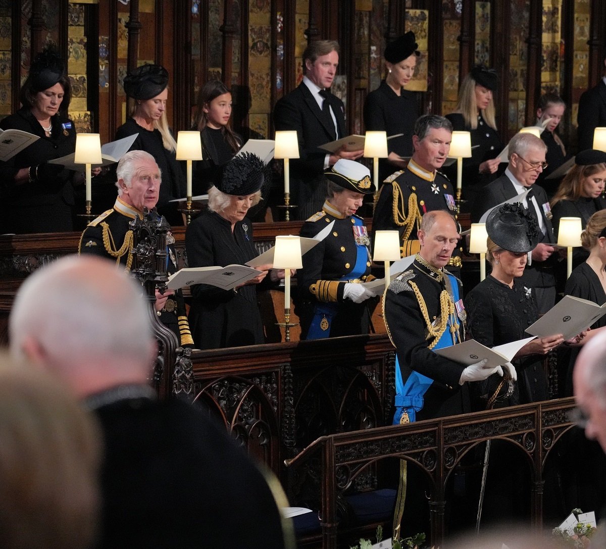 King Charles III standing in front of one empty seat at St. George's Chapel with other royals at Queen Elizabeth II's committal service