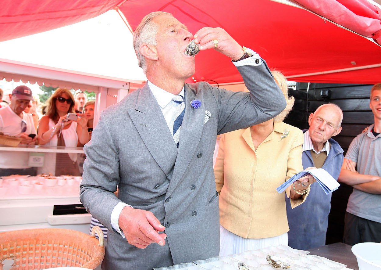 King Charles III samples an oyster at the Whitstable Oyster Festival in 2013. Charles' coronation celebration will follow one longstanding royal tradition with a little help from an invasive parasitic fish in the U.S.