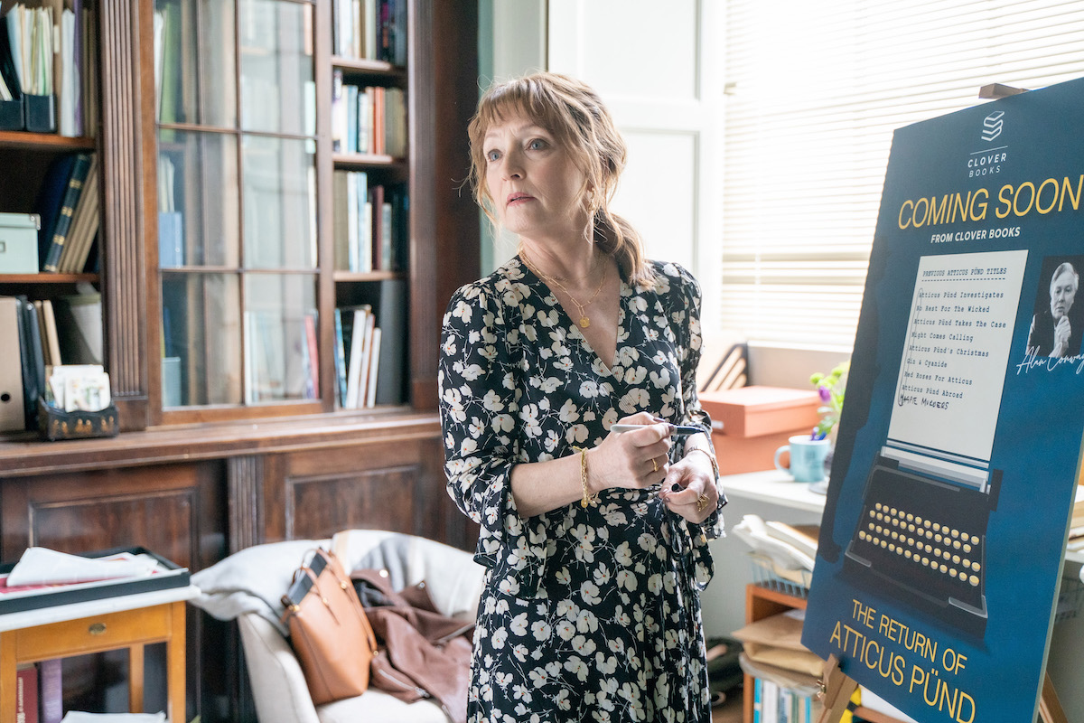 Lesley Manville standing in front of a poster advertising a new book in the PBS series 'Magpie Murders'