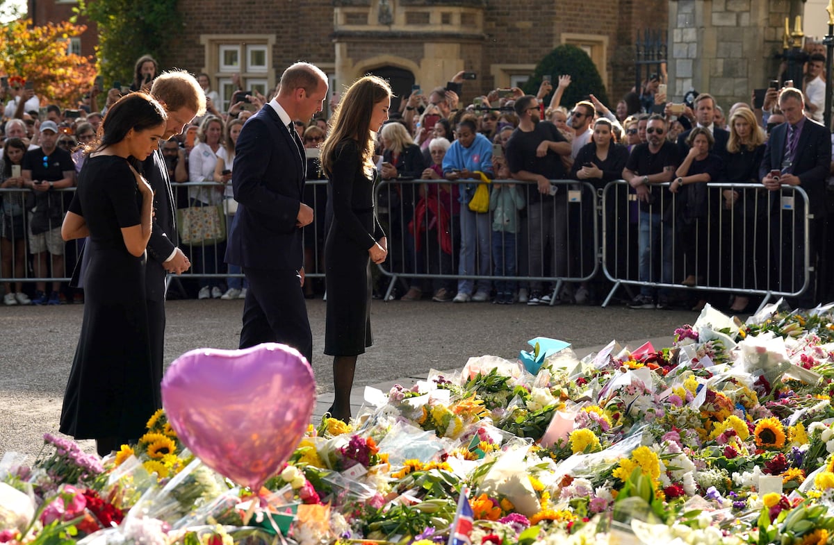 Meghan Markle, Prince Harry, Prince William, and Kate Middleton, who, according to a body language expert, made her feelings about Meghan Markle clear from the start of the Windsor Castle walkabout, look at tributes to Queen Elizabeth II