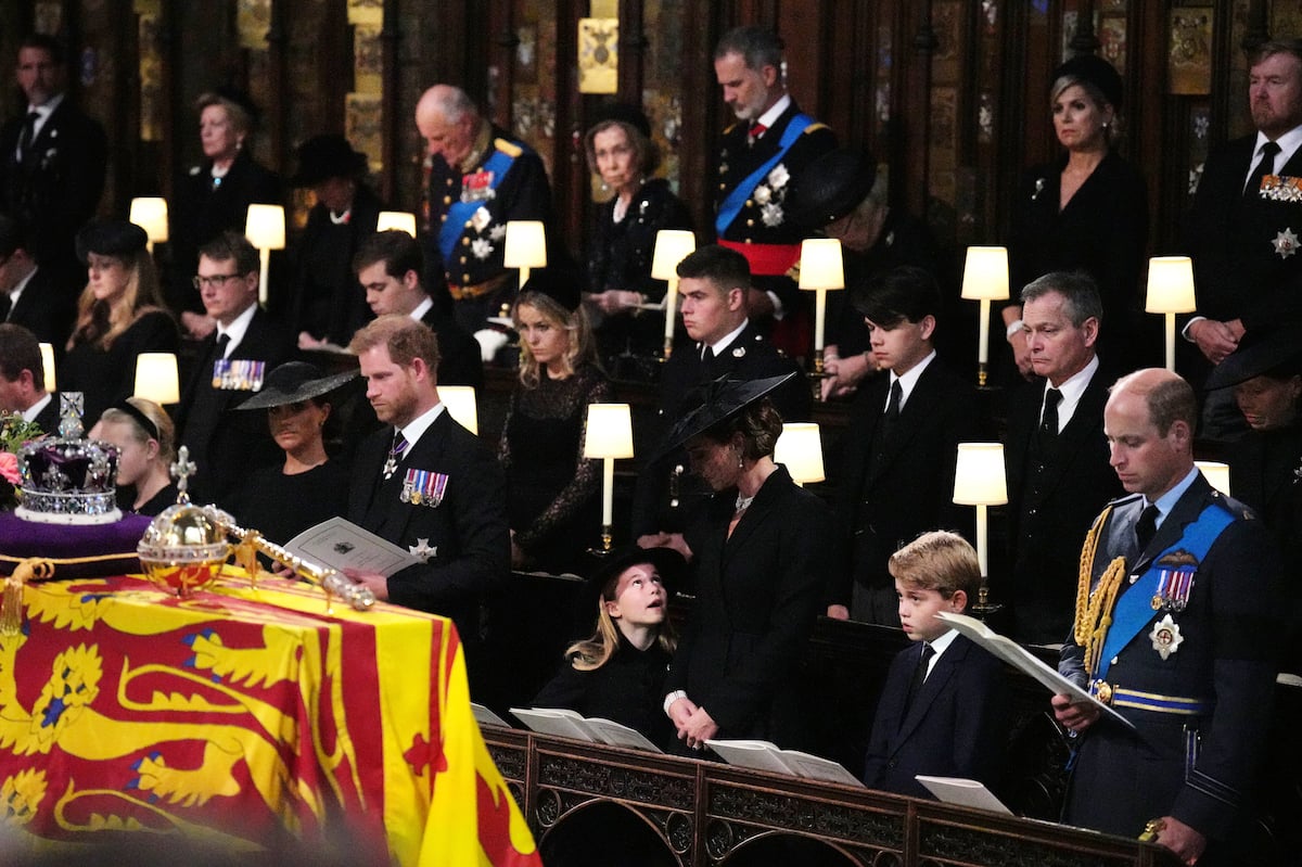 Meghan Markle sits next to Prince Harry, who, according to a lip reader, got a five-word reply from Prince William to a question, as Princess Charlotte, Kate Middleton, Prince George, and Prince William are nearby during Queen Elizabeth's funeral at St. George's Chapel