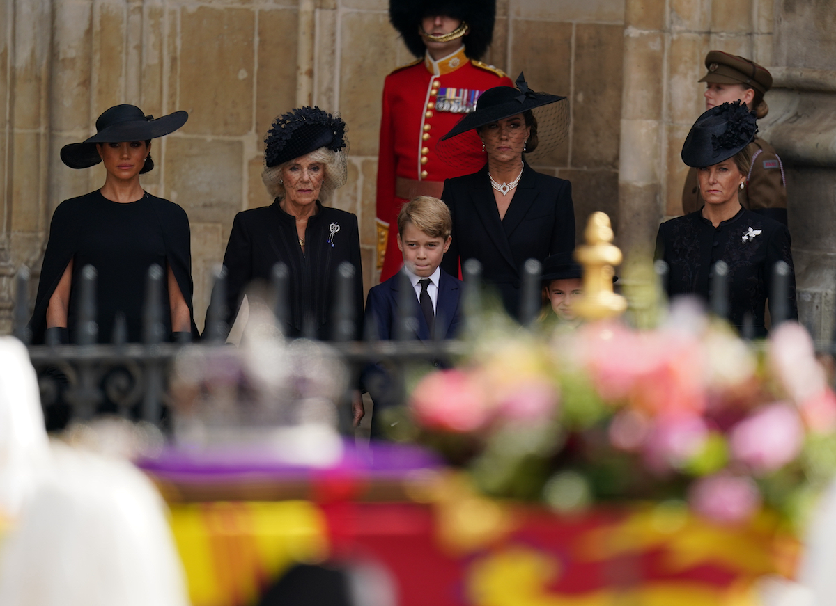 Meghan Markle, Queen Consort Camilla, Prince George, Kate Middleton, Princess Charlotte, and Sophie, Countess of Wessex stand outside Westminster Abbey at a state funeral service for Queen Elizabeth II