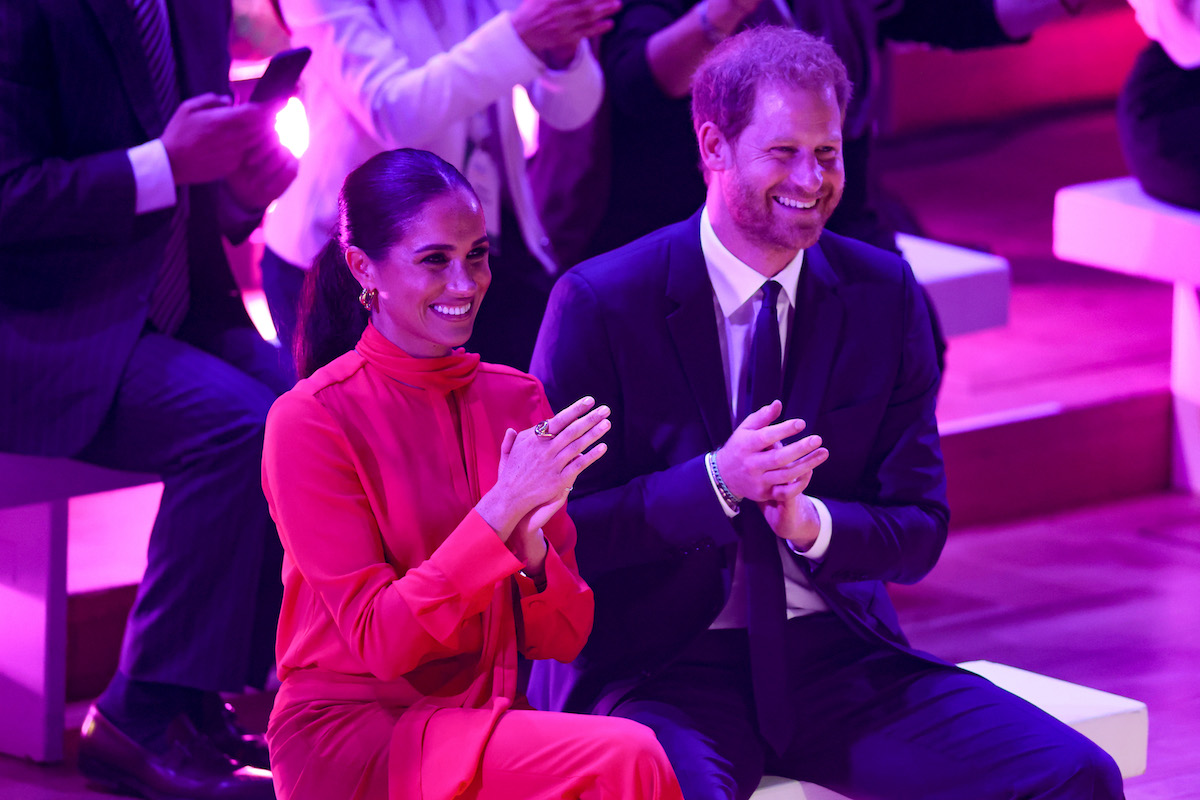 Meghan Markle, who some commentators criticized for her One Young World Summit opening ceremony speech, claps and smiles alongside Prince Harry at the 2022 One Young World Summit opening ceremony