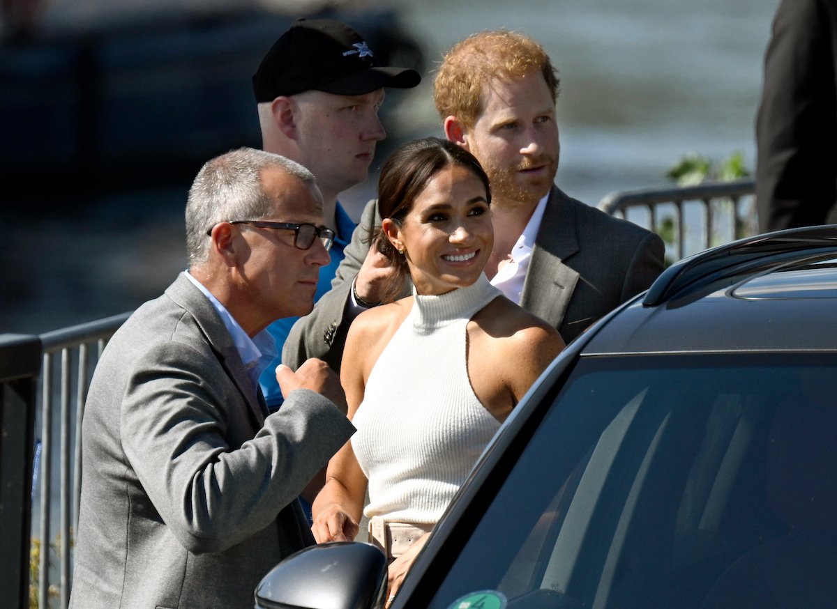 Prince Harry and Meghan Markle, who were criticized for tutoring Archie's backpack in The Cut interview, smile as they get out of the car