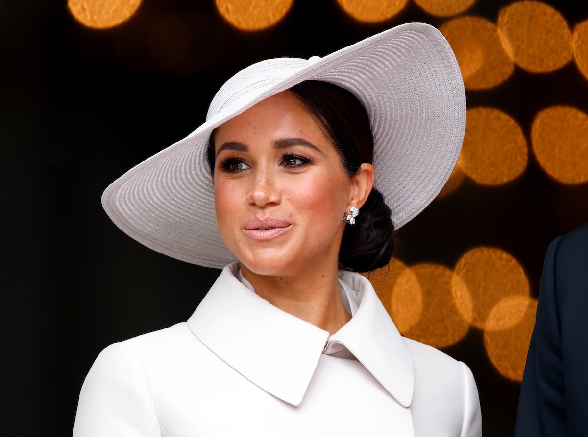 Meghan Markle, who a royal commentator says 'annoyed' people by challenging princess idea, looks on wearing a white hat