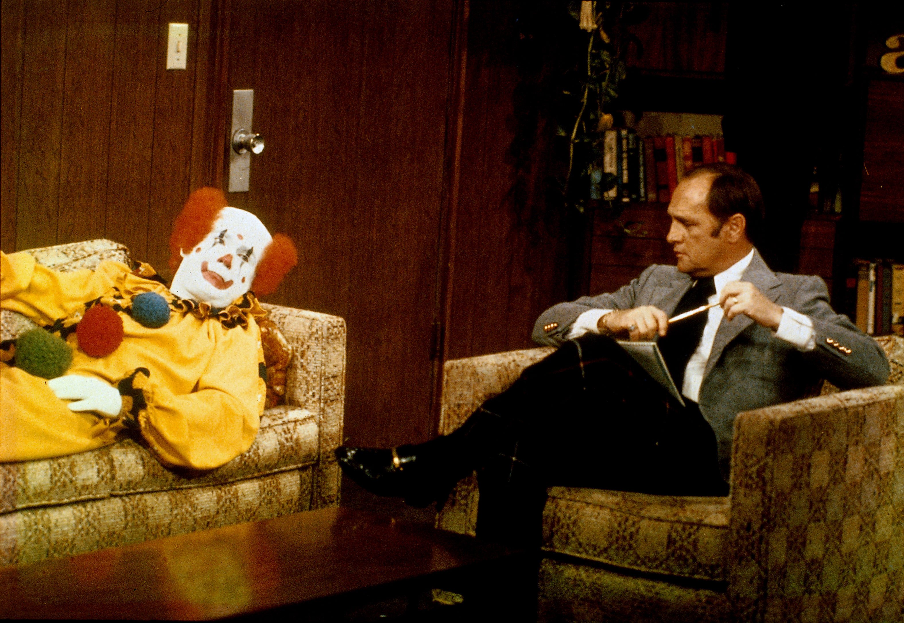 A clown lies on a couch and tells his problems to American comedian and actor Bob Newhart, who plays a psychiatrist in 'The Bob Newhart Show,'