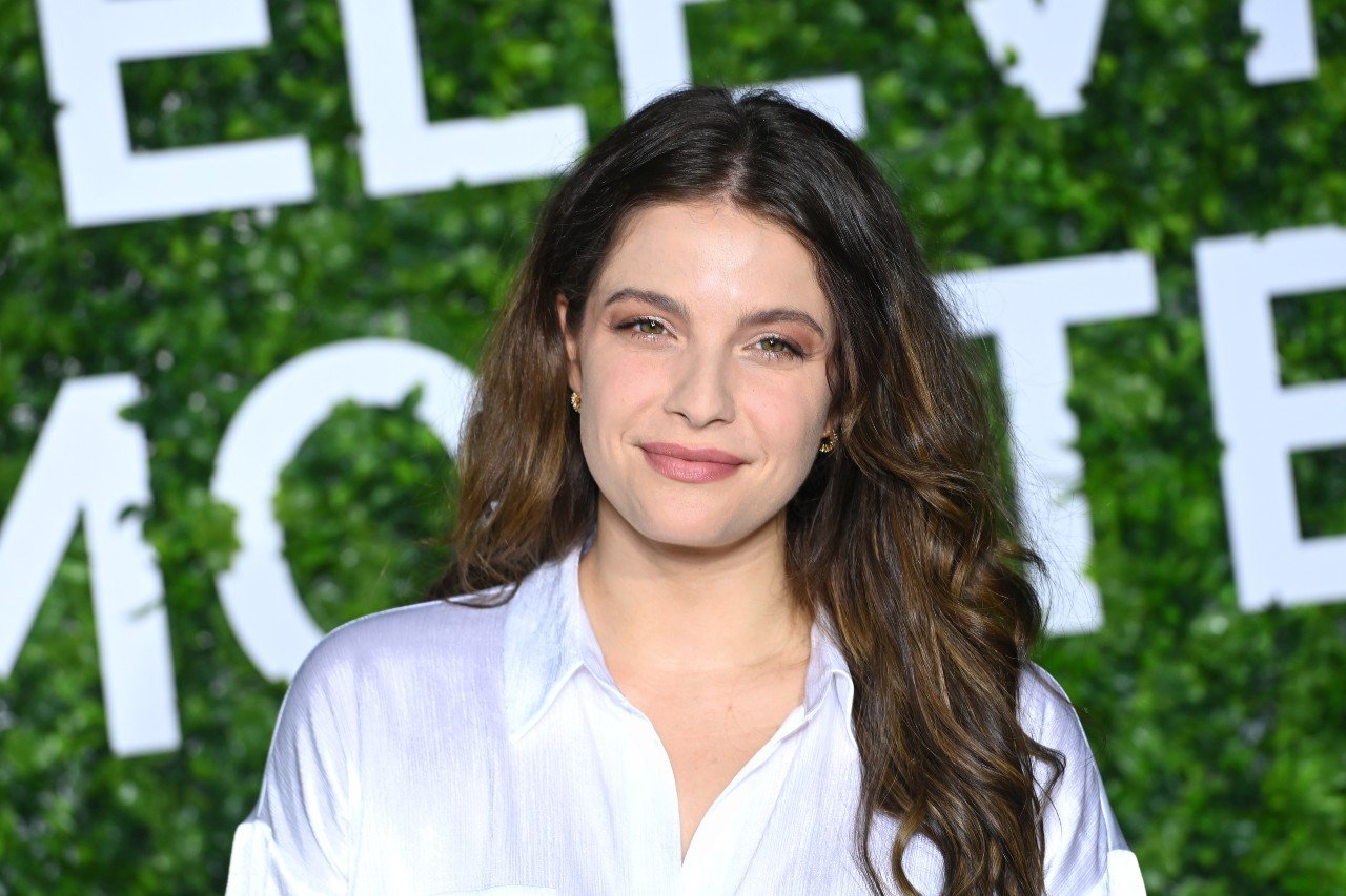 Paige Spara poses in a white shirt during a media event. 