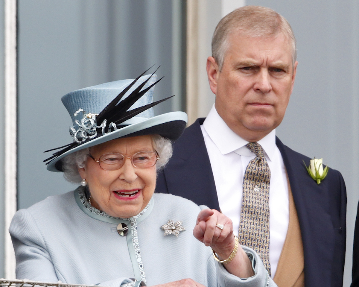 Prince Andrew wearing a suit and standing behind Queen Elizabeth, whose corgis he'll inherit.