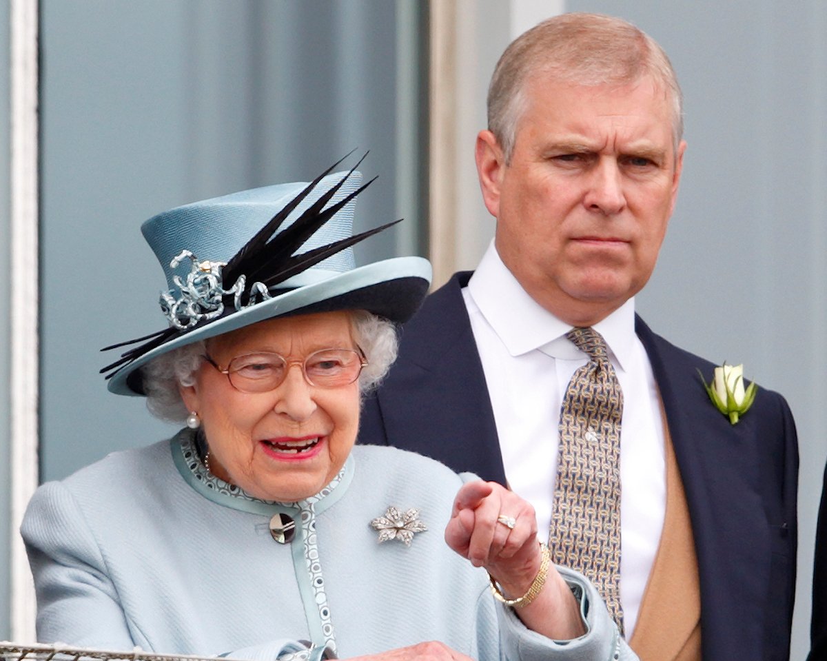 Prince Andrew wearing a suit and standing behind Queen Elizabeth, whose corgis he'll inherit.