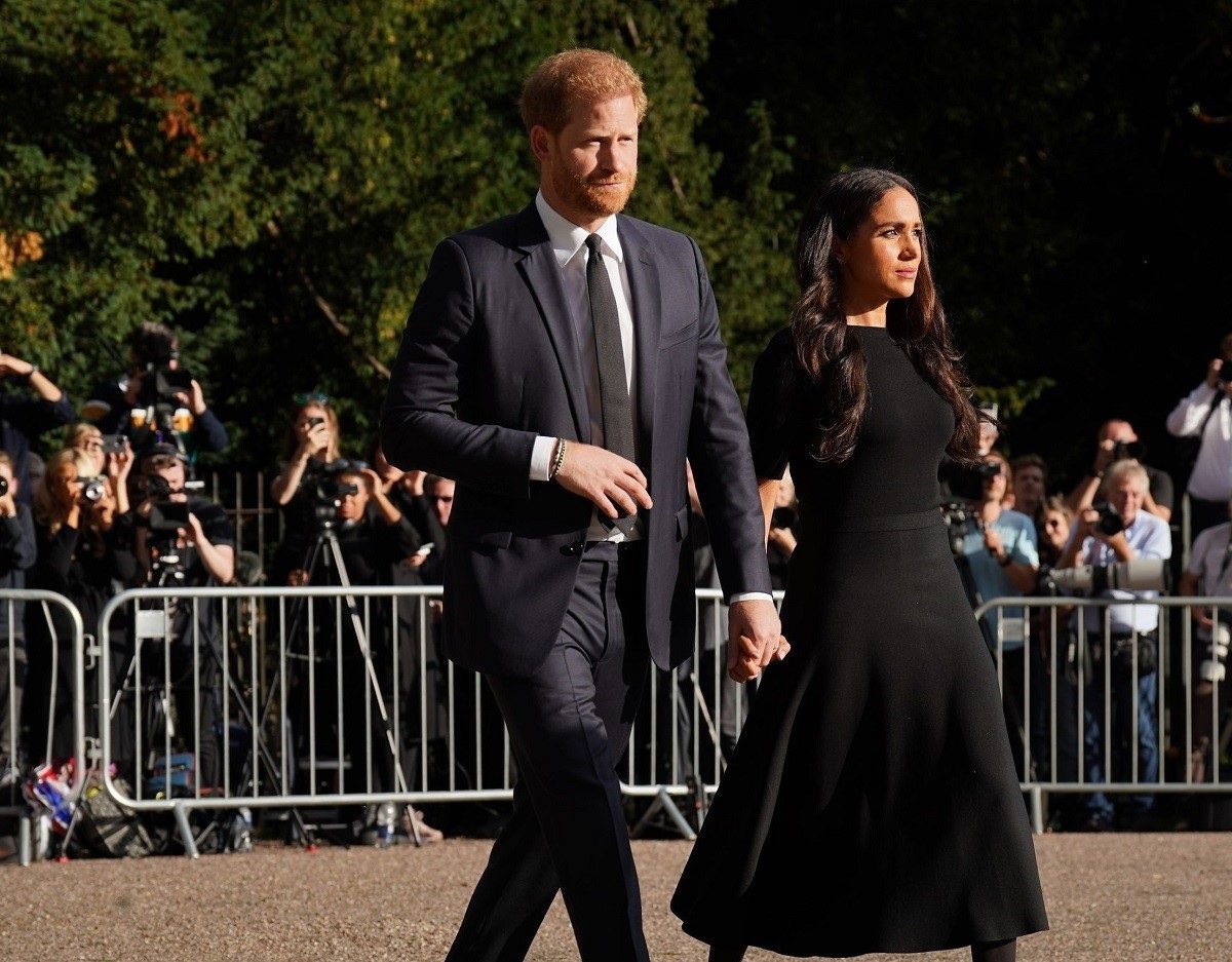 Prince Harry and Meghan Markle, who have a news book out about them with some of the biggest bombshells yet, view floral tributes left at Windsor Castle following Queen Elizabeth's death