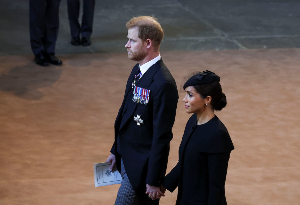 Prince Harry and Meghan Markle, who commentators say won't bring Archie and Lilibet to Queen Elizabeth's funeral, walk side by side wearing black at Westminster Hall