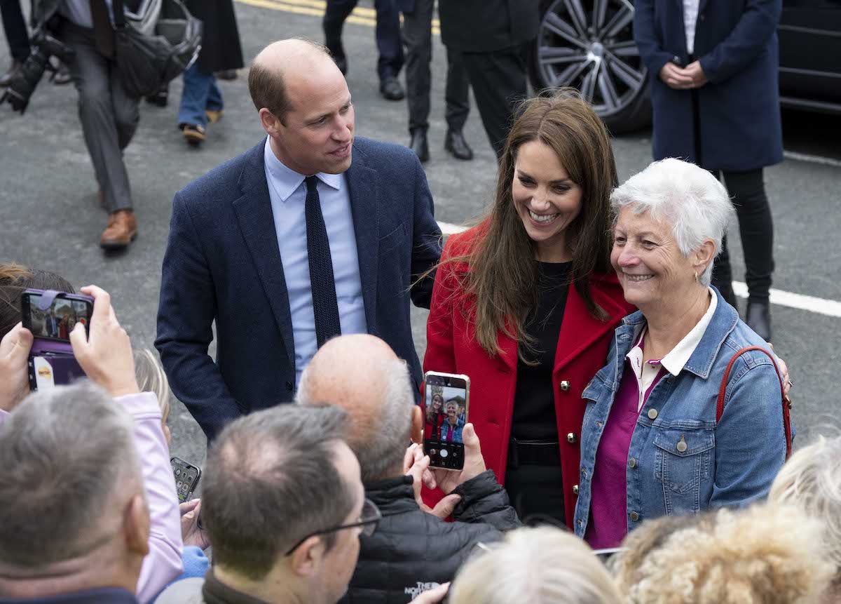 Prince William looks at Kate Middleton as she poses for a photo with a well-wisher during a visit to Wales on Sept. 27, 2022