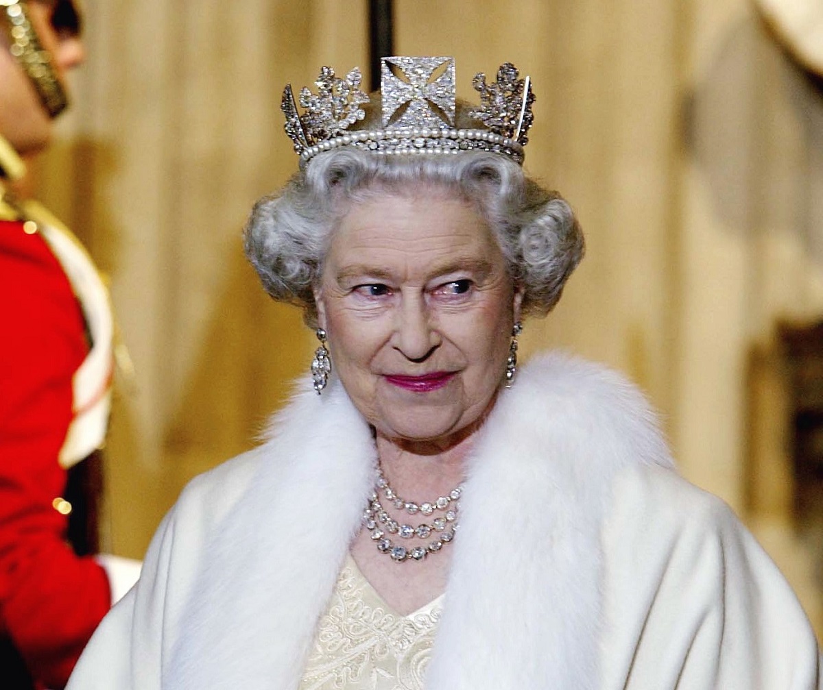 Queen Elizabeth II, who has an impressive jewelry collection with pieces that could go to Kate Middleton and Meghan Markle, smiling as she arrives for the state opening of Parliament