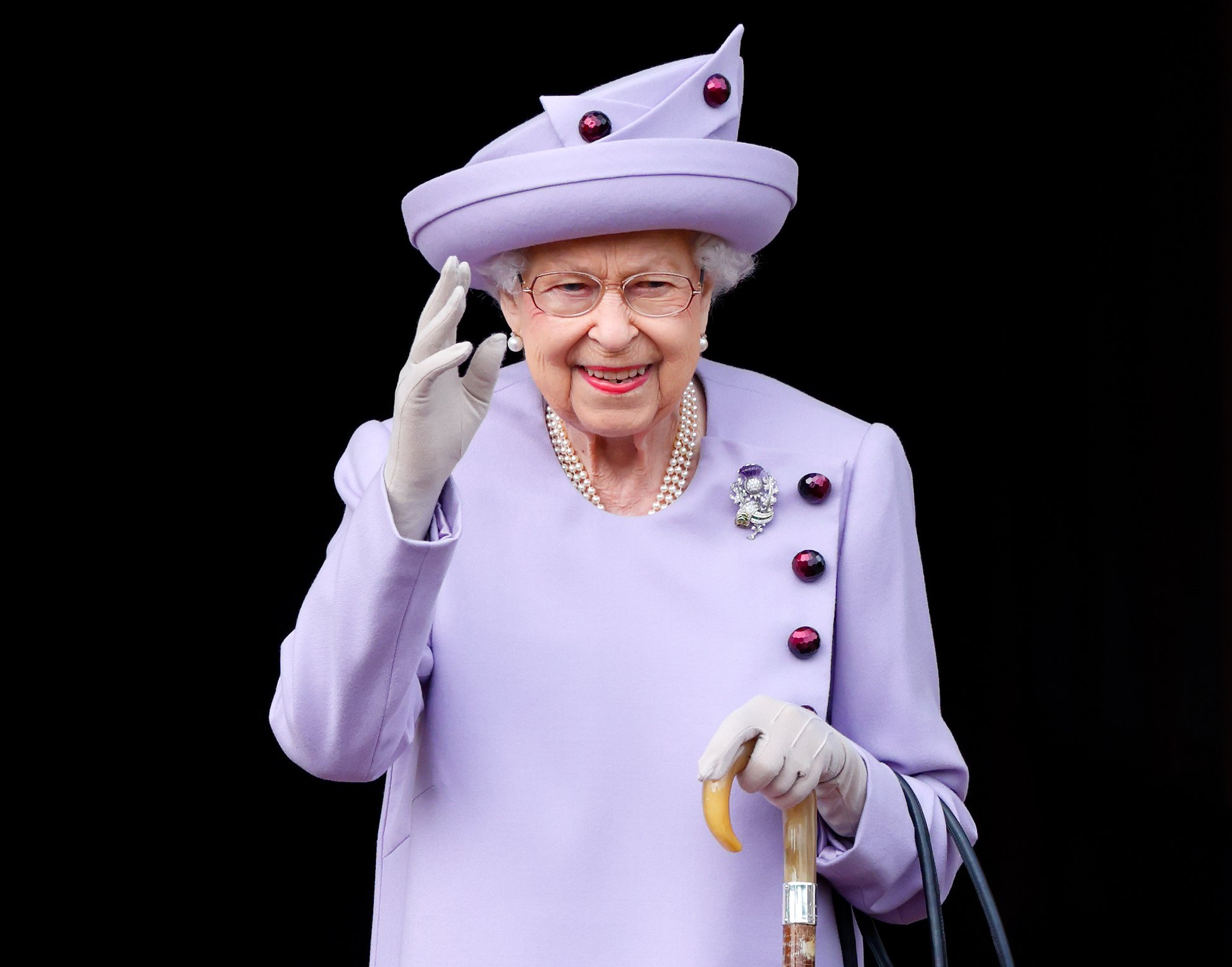 Queen Elizabeth II, who died at the age of TK on TK, waves wearing a purple outfit