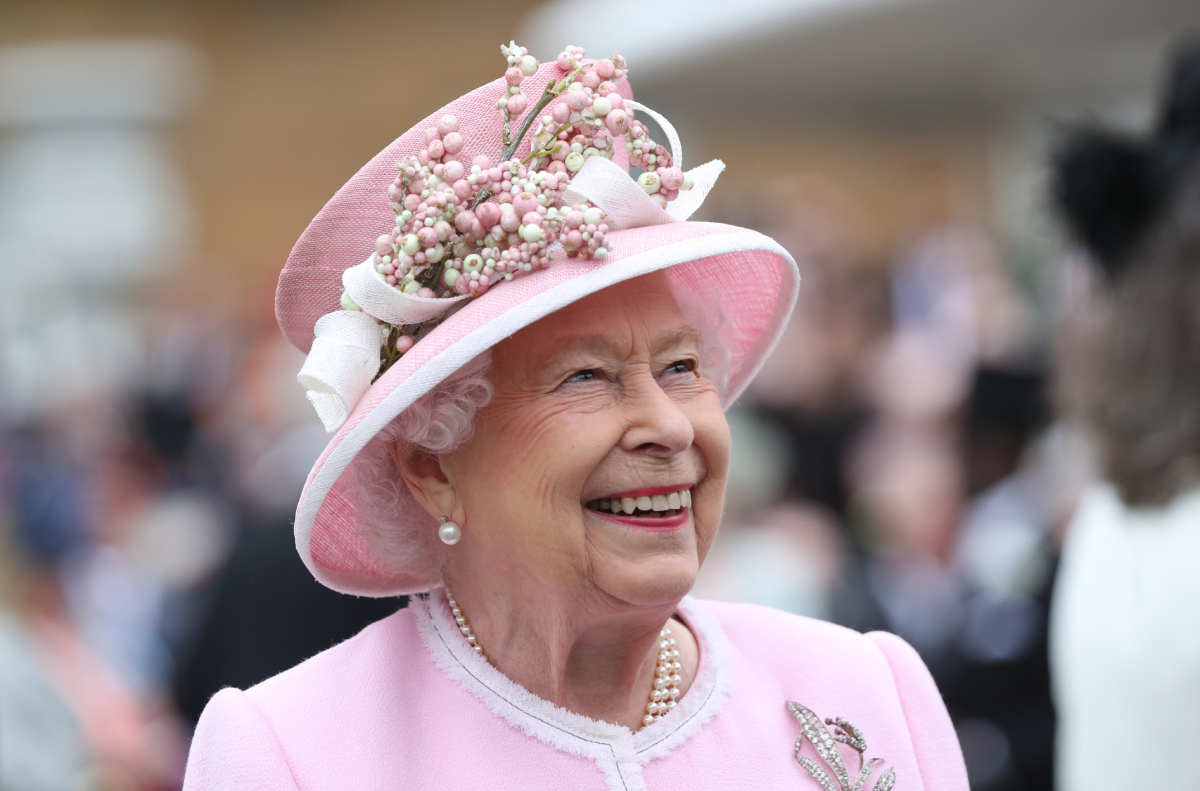 Queen Elizabeth II wears a pink hat, jacket, and skirt as she meets guests as she attends the Royal Garden Party at Buckingham Palace on May 29, 2019 in London, England