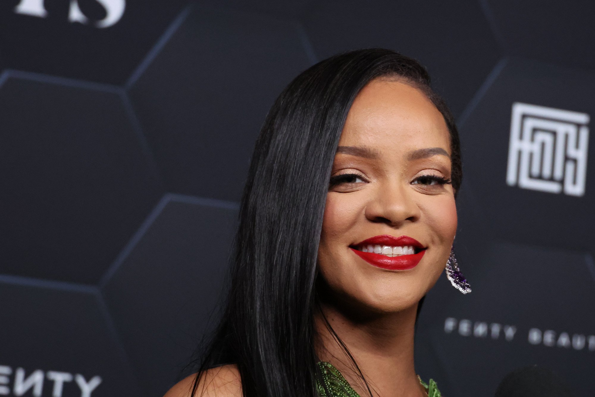 2023 Super Bowl performer Rihanna smiling against a black backdrop