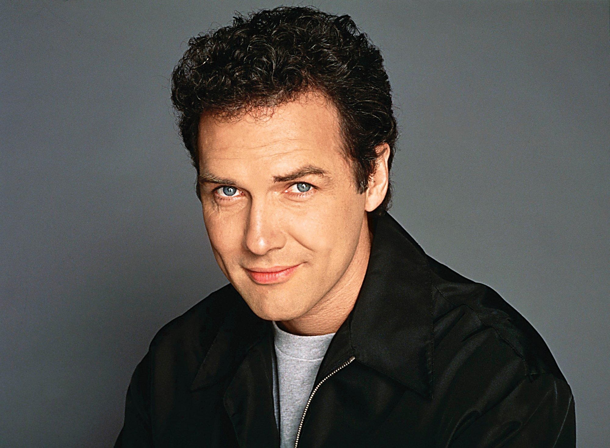 'Saturday Night Live' Norm Macdonald with a closed-mouth smile. He's wearing zip-up jacket and a grey crewneck shirt underneath.