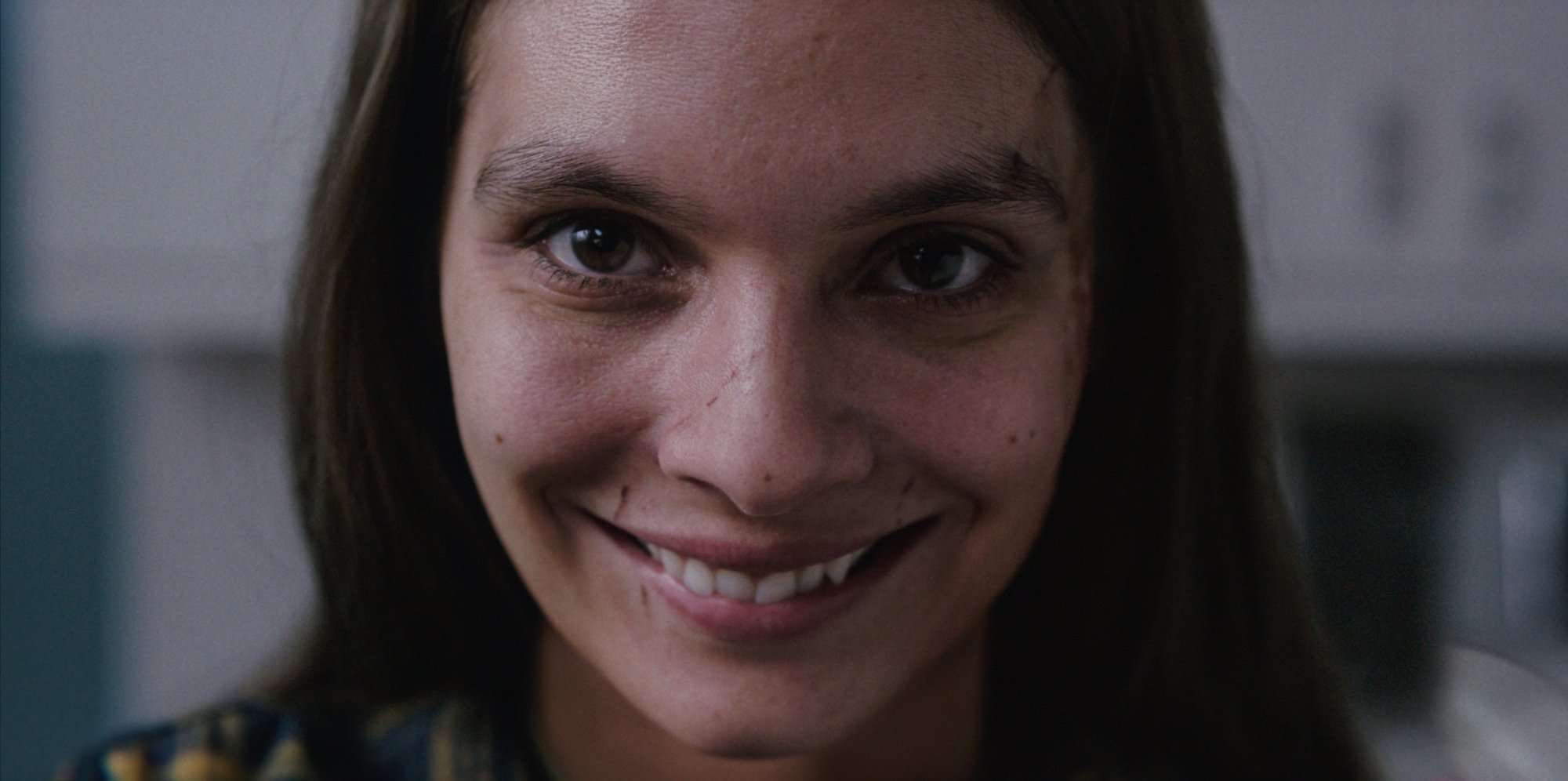 'Smile' Caitlin Stasey as Laura Weaver with a wide smile on her face