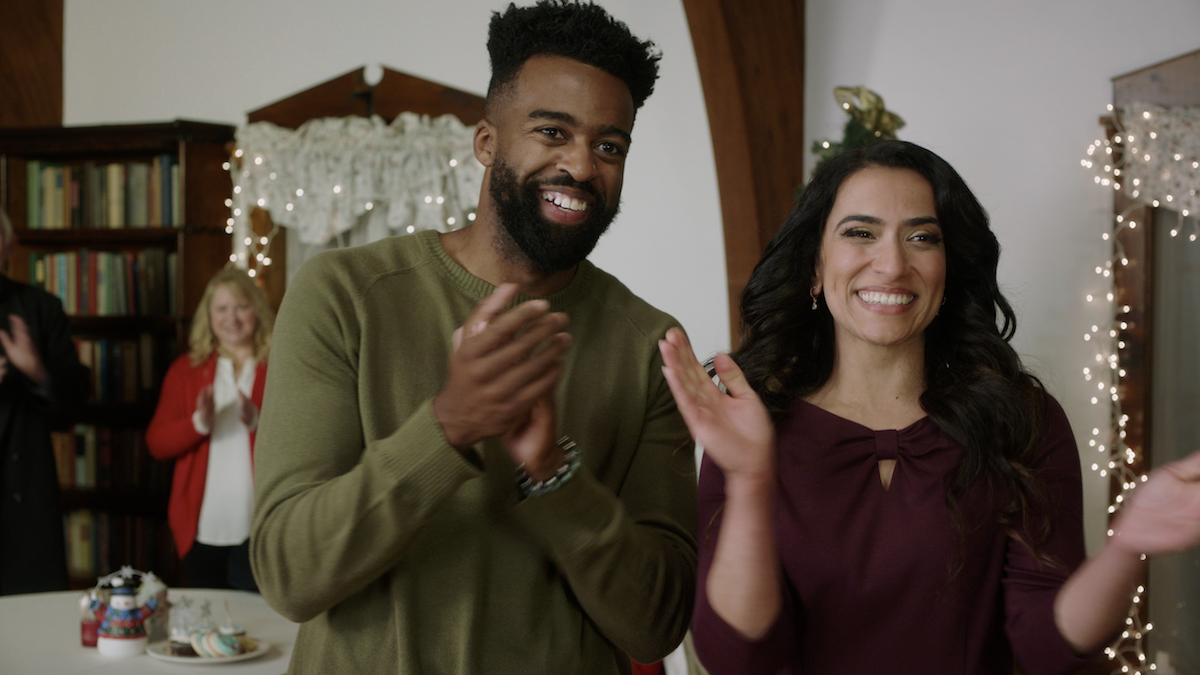 A man and a woman clapping in the UPtv 2022 Christmas movie 'The Snowball Effect'