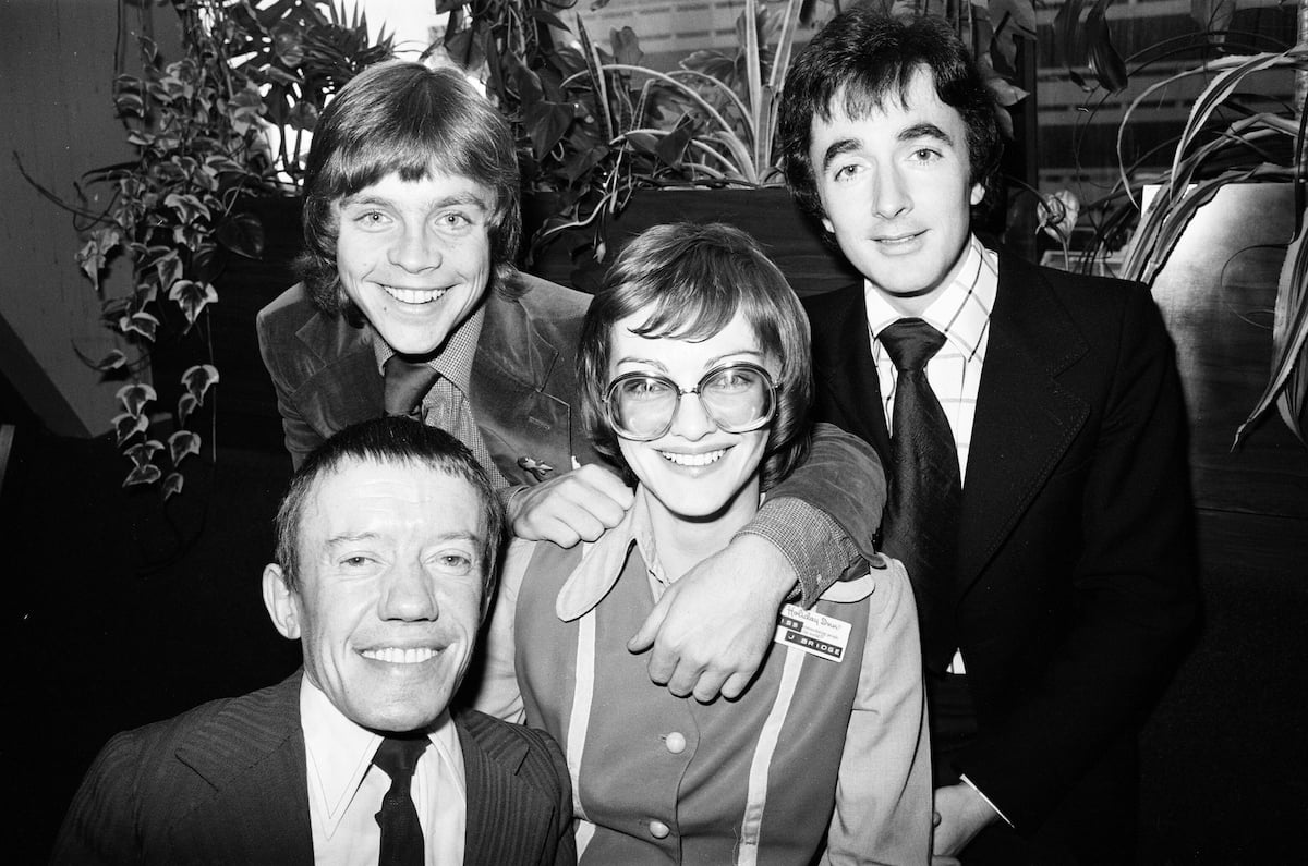 Mark Hamill, Kenny Baker, and Anthony Daniels pose with a fan at a Star Wars event in 1978