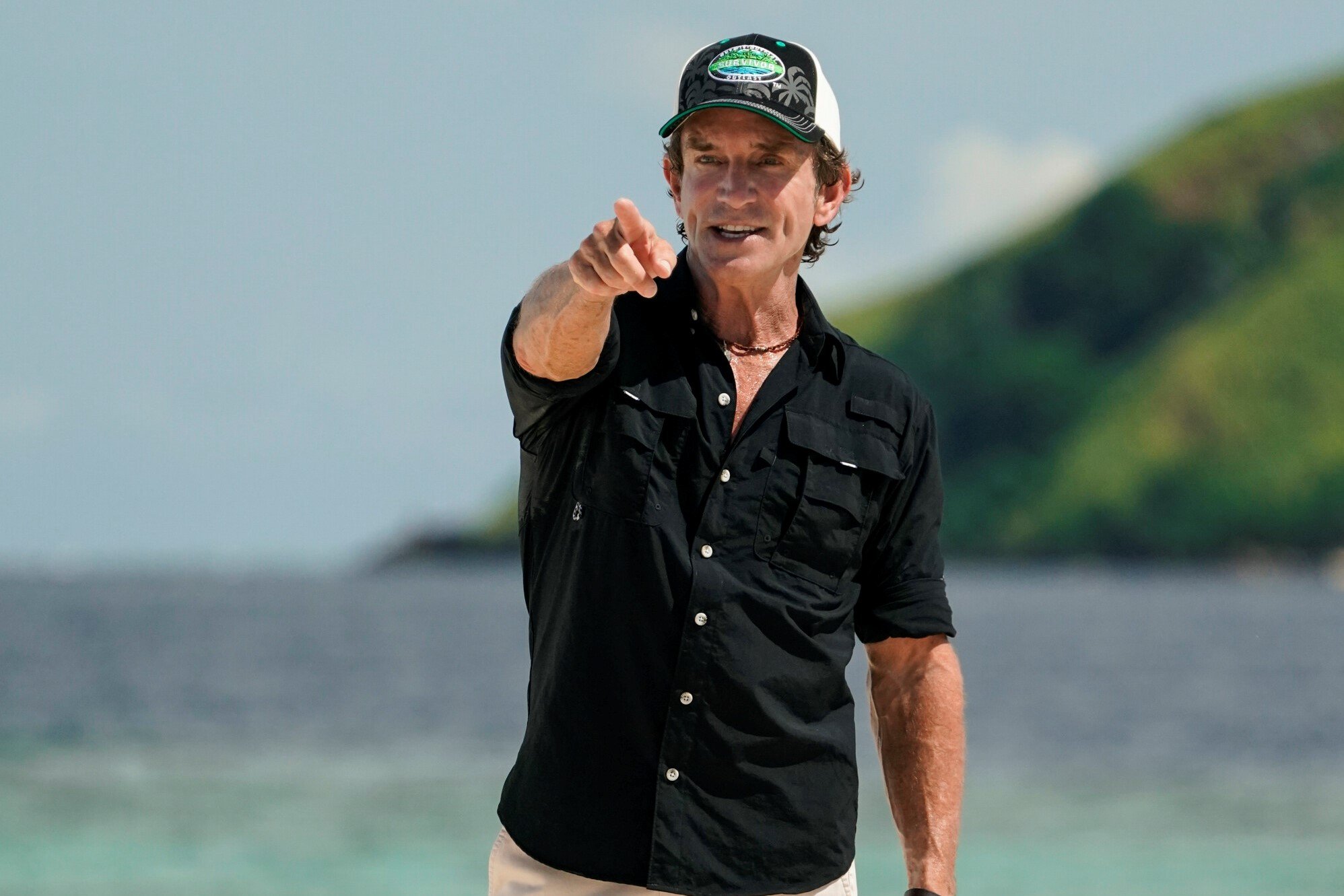 Jeff Probst, who explains twists in 'Survivor' Season 43 on CBS, wears a black button-up shirt and a black, white, and green 'Survivor' baseball cap.