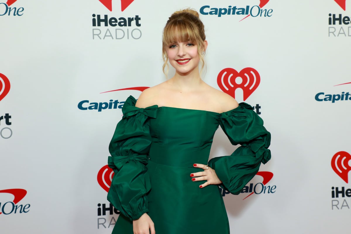 The Handmaid's Tale star Mckenna Grace wears a green off-the-shoulder dress and has blonde hair in an up-do.