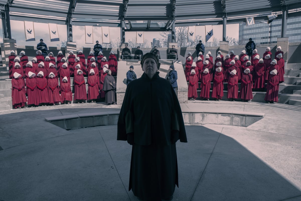 Ann Dowd will return as Aunt Lydia in The Handmaid's Tale Season 5. Aunt Lydia stands in front of an assembly of handmaids.