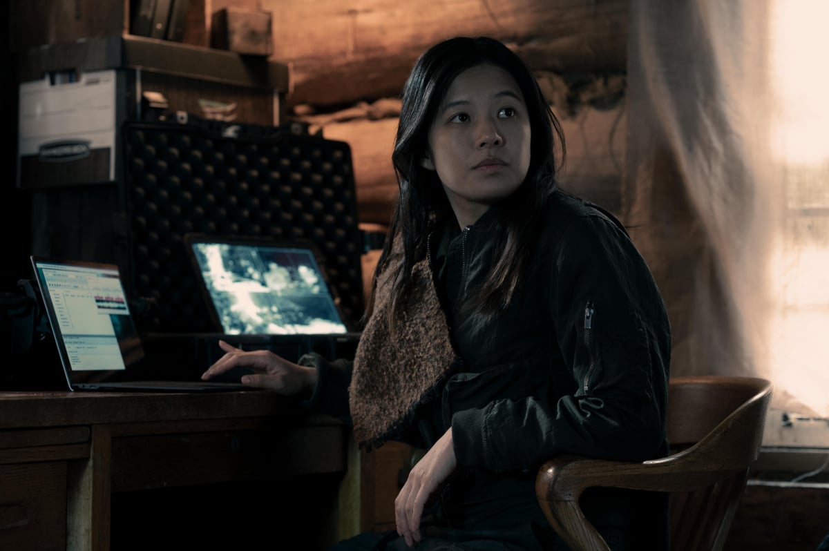 Christine Ko als Lily in Staffel 5 von The Handmaid's Tale. Lily sitzt an einem Schreibtisch in einem Mayday-Außenposten.