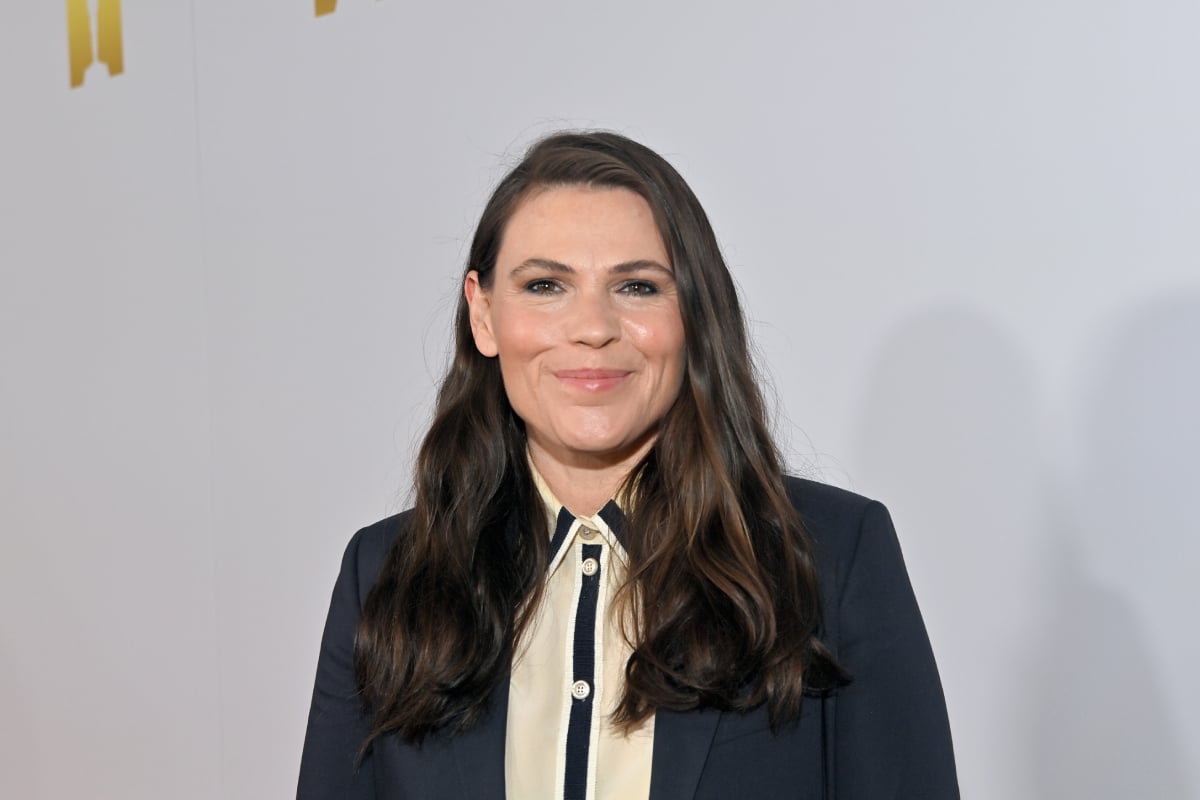Clea DuVall will return to her role as Sylvia in The Handmaid's Tale Season 5. DuVall wears a button-up shirt and dark blue suit jacket.