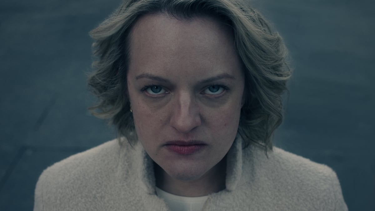 Elisabeth Moss as June in The Handmaid's Tale Season 5. June wears a white jacket and looks angry. 