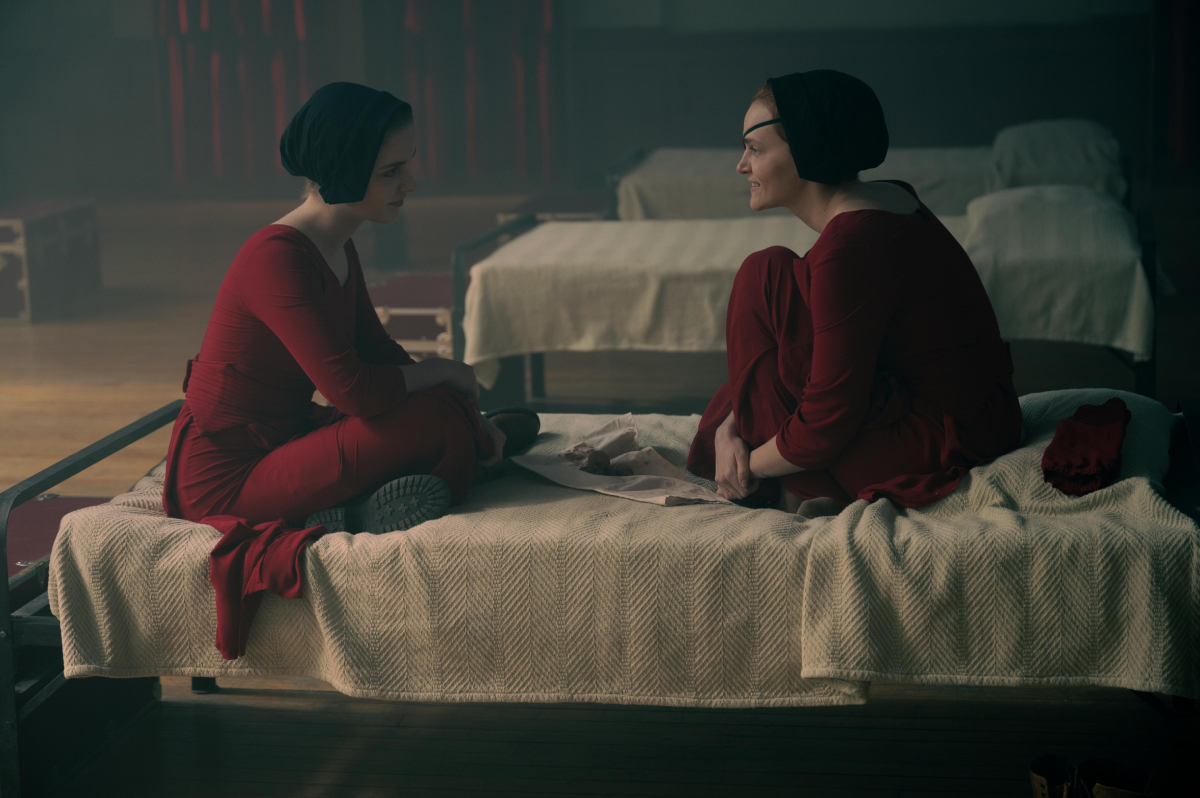In Staffel 5 von The Handmaid’s Tale sitzen Janine (Madeline Brewer) und Esther Keyes (McKenna Grace) auf einem Bett im Roten Zentrum.