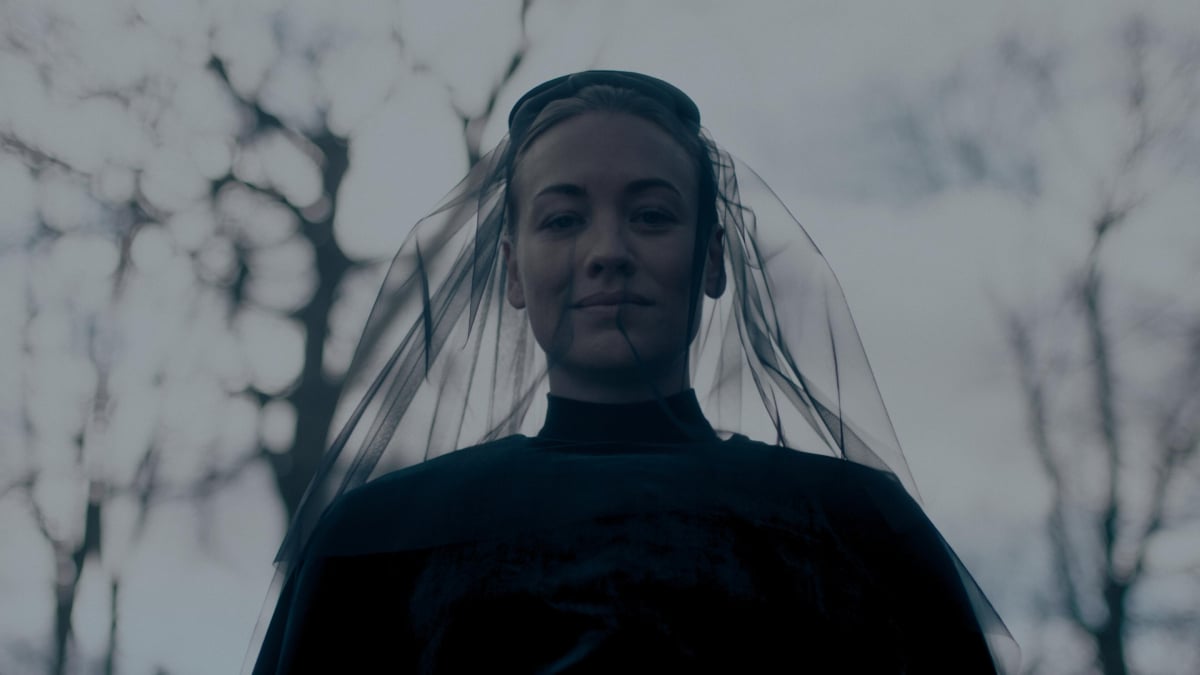 Yvonne Strahovski as Serena Joy Waterford in The Handmaid's Tale Season 5. Serena wears all black with a veil over her face and smiles.