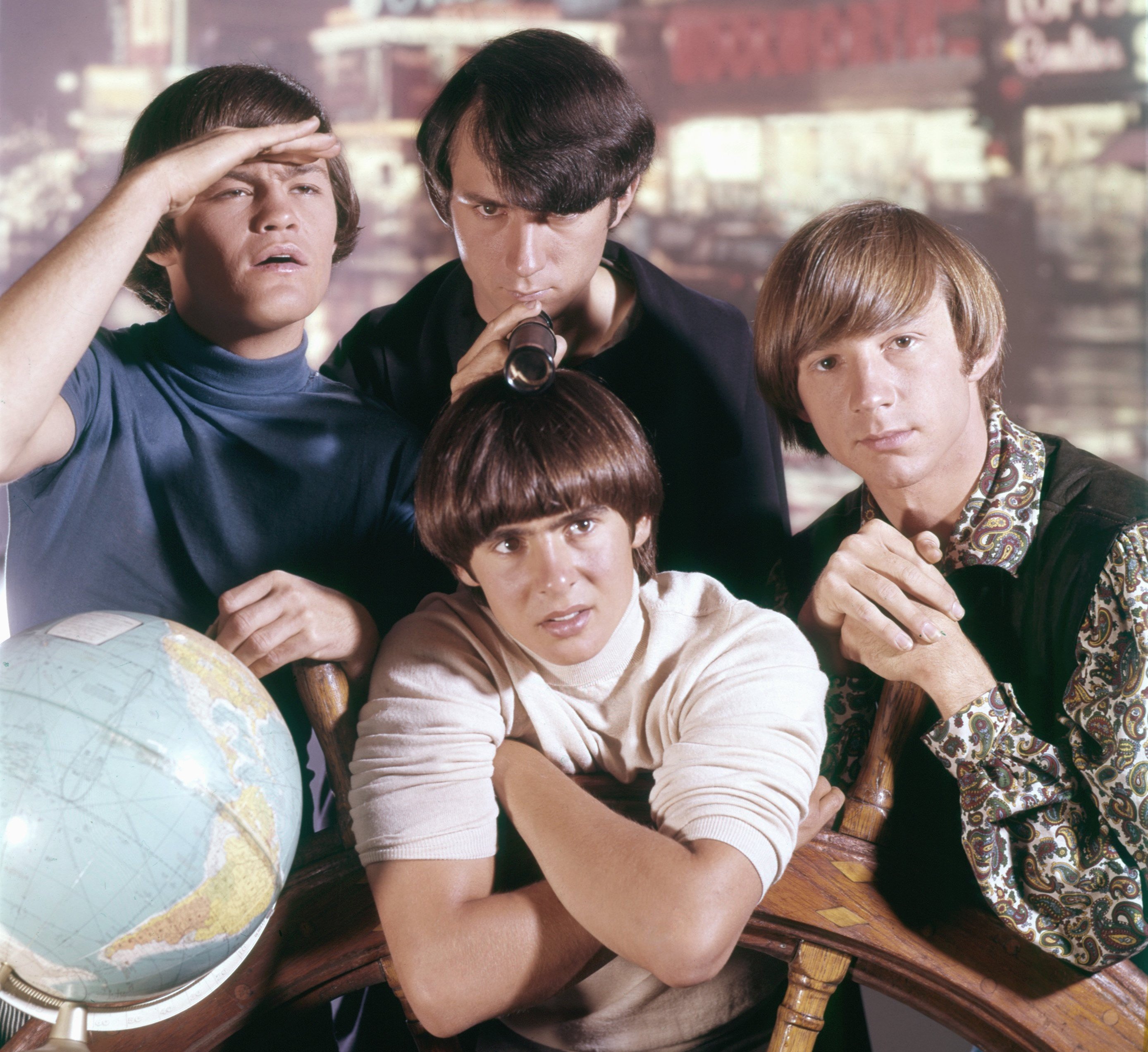 The Monkees' Micky Dolenz, Mike Nesmith, Davy Jones, and Peter Tork with a globe