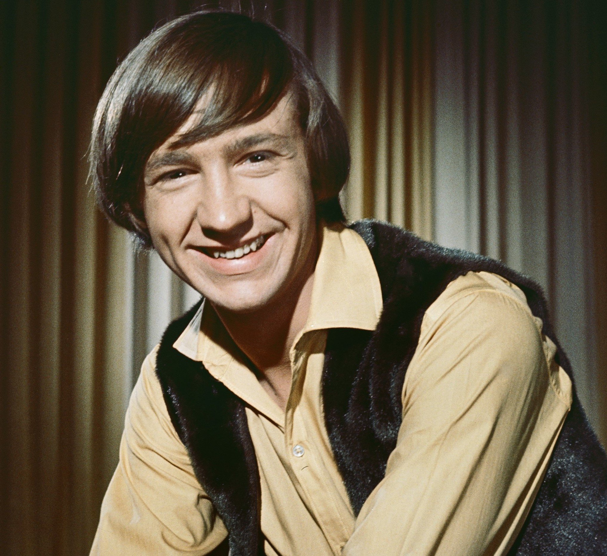 The Monkees' Peter Tork in front of a curtain