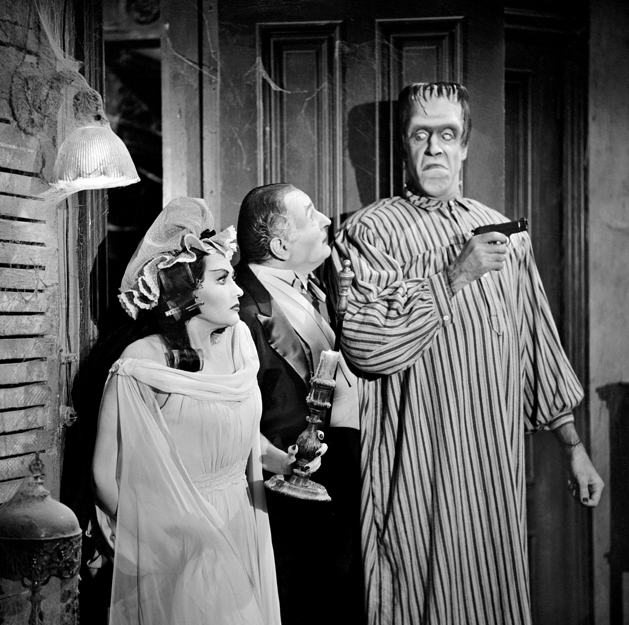 'The Munsters' stars Yvonne De Carlo, Al Lewis, and Fred Gwynne in a black and white photo from the show.