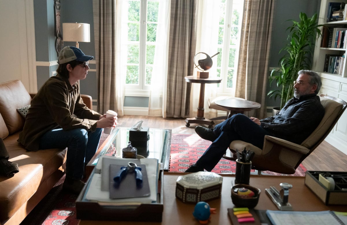 Domhnall Gleeson as Sam and Steve Carell as Alan in The Patient. Sam and Alan talk on either side of a glass table in Alan's office. Alan wears a hat and sunglasses. 