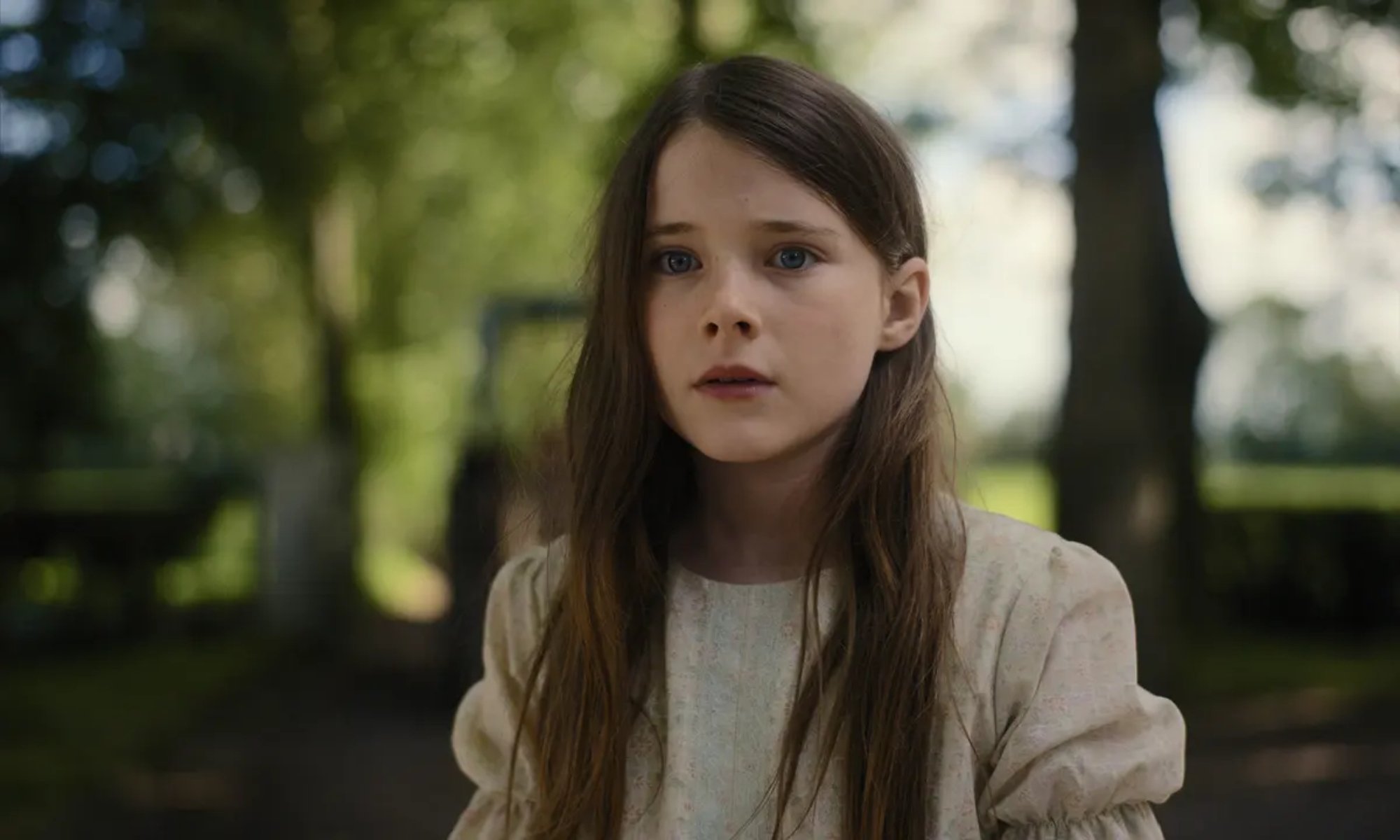 'The Quiet Girl' Catherine Clinch as Cáit wearing a white dress looking worried with greenery in the background