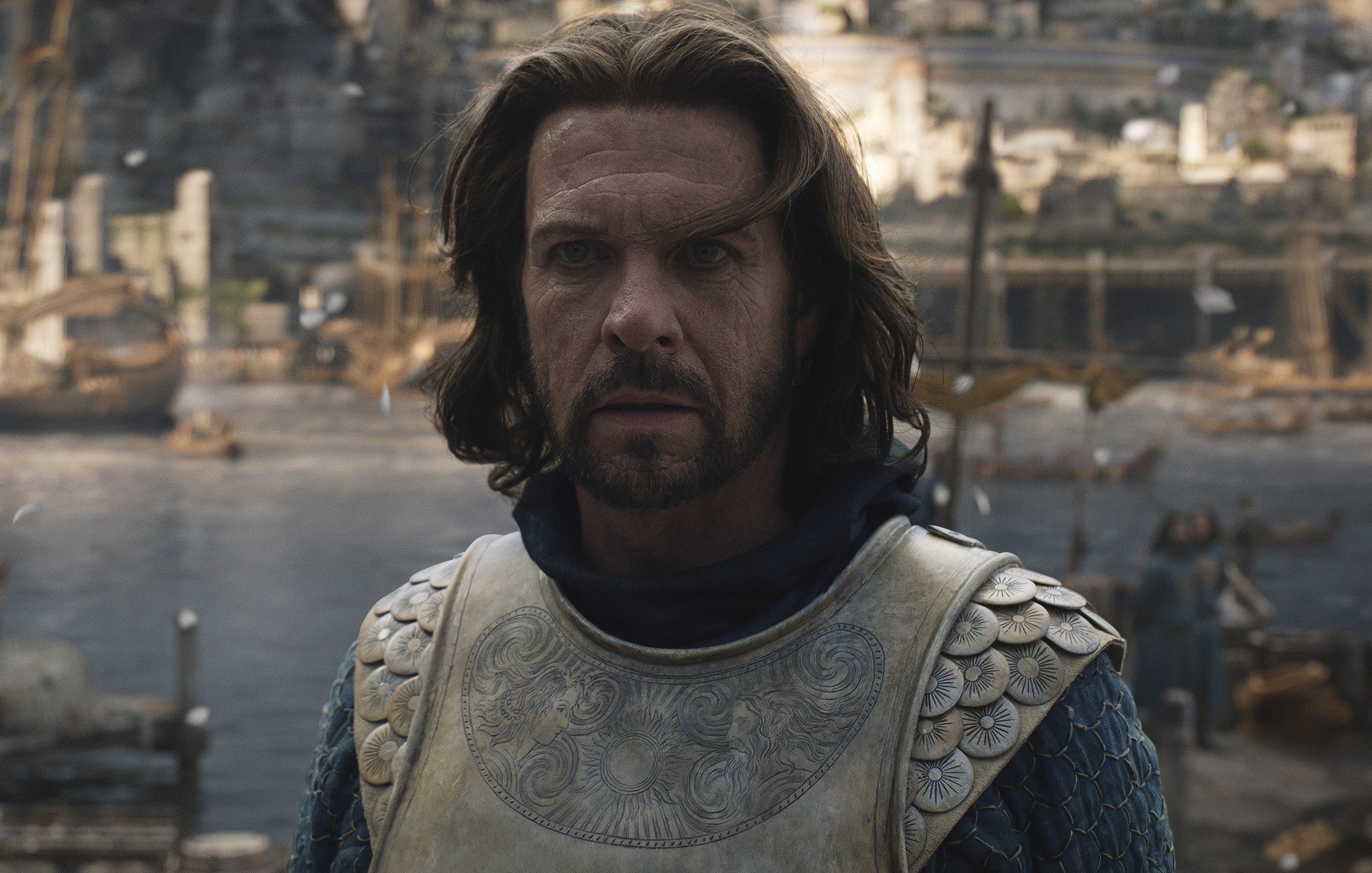 Lloyd Owen as Elendil in 'The Lord of the Rings: The Rings of Power.' He's wearing armor, and something is on fire behind him.