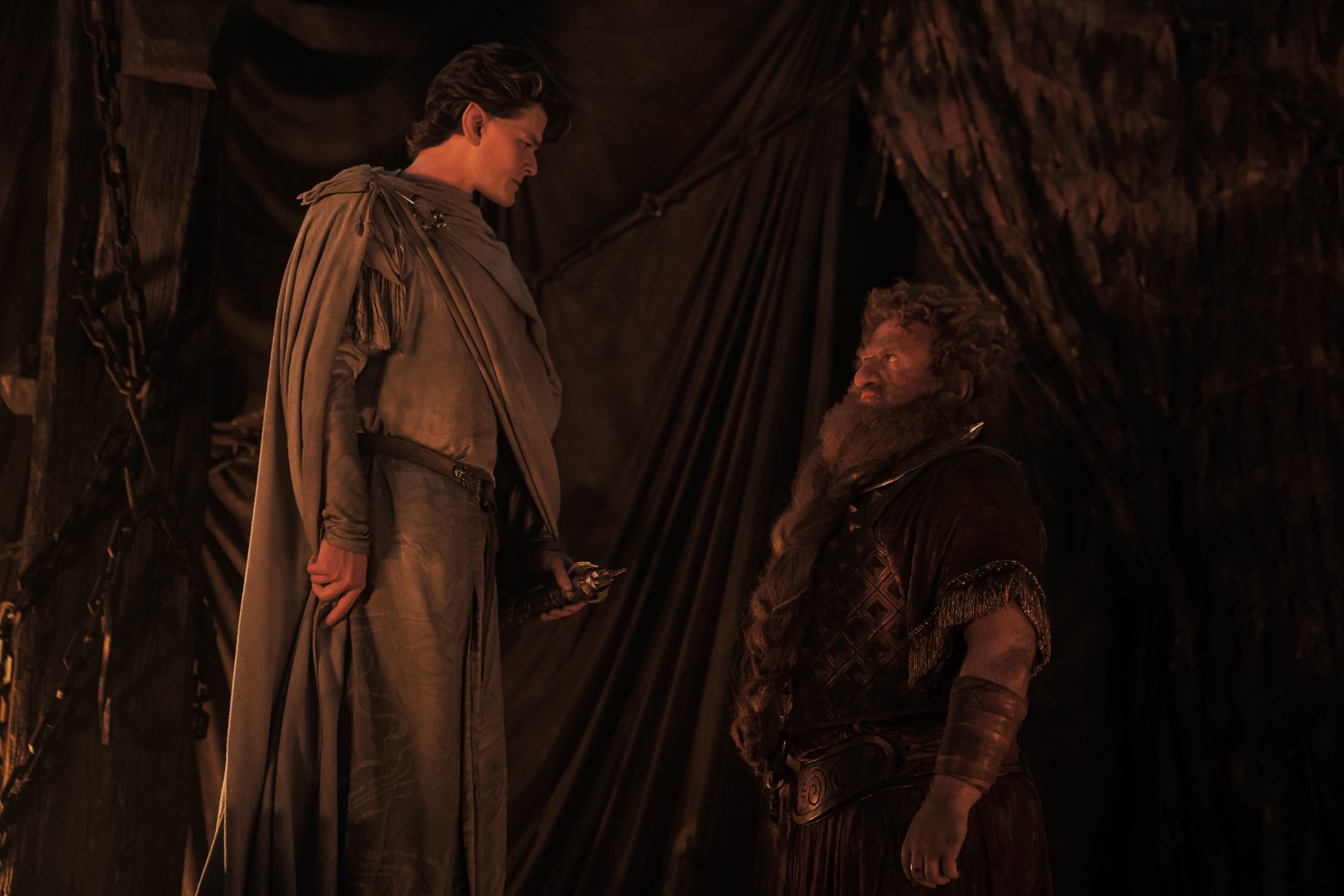 Robert Aramayo and Owain Arthur as Elrond and Durin in 'The Rings of Power' Episode 4, where they discuss Mithril. The two are in a dark mine facing one another.
