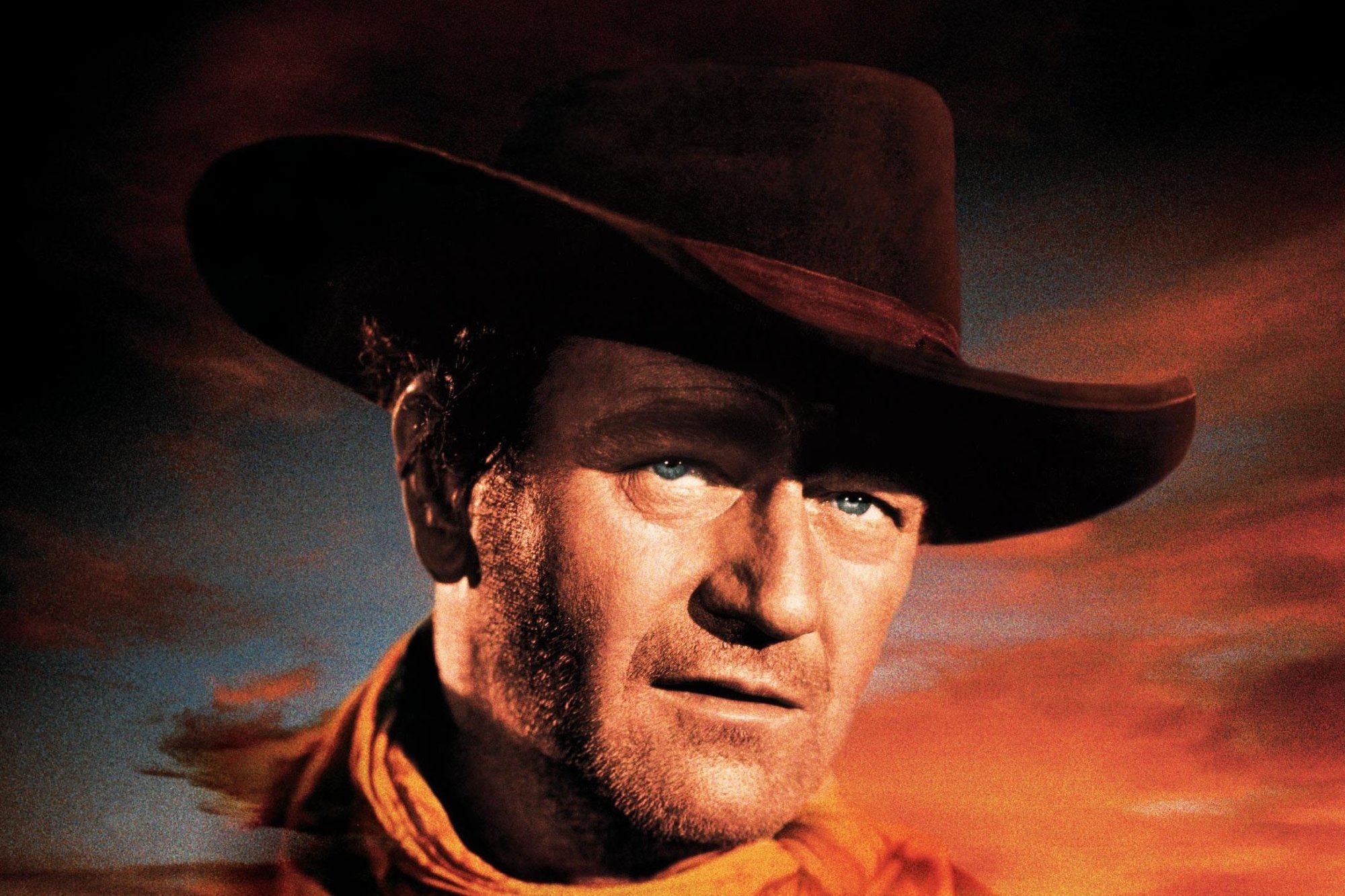 'The Searchers' starring John Wayne, Natalie Wood, and Jeffrey Hunter. Poster showing Wayne wearing a cowboy hat looking ahead with a sunset in the background.