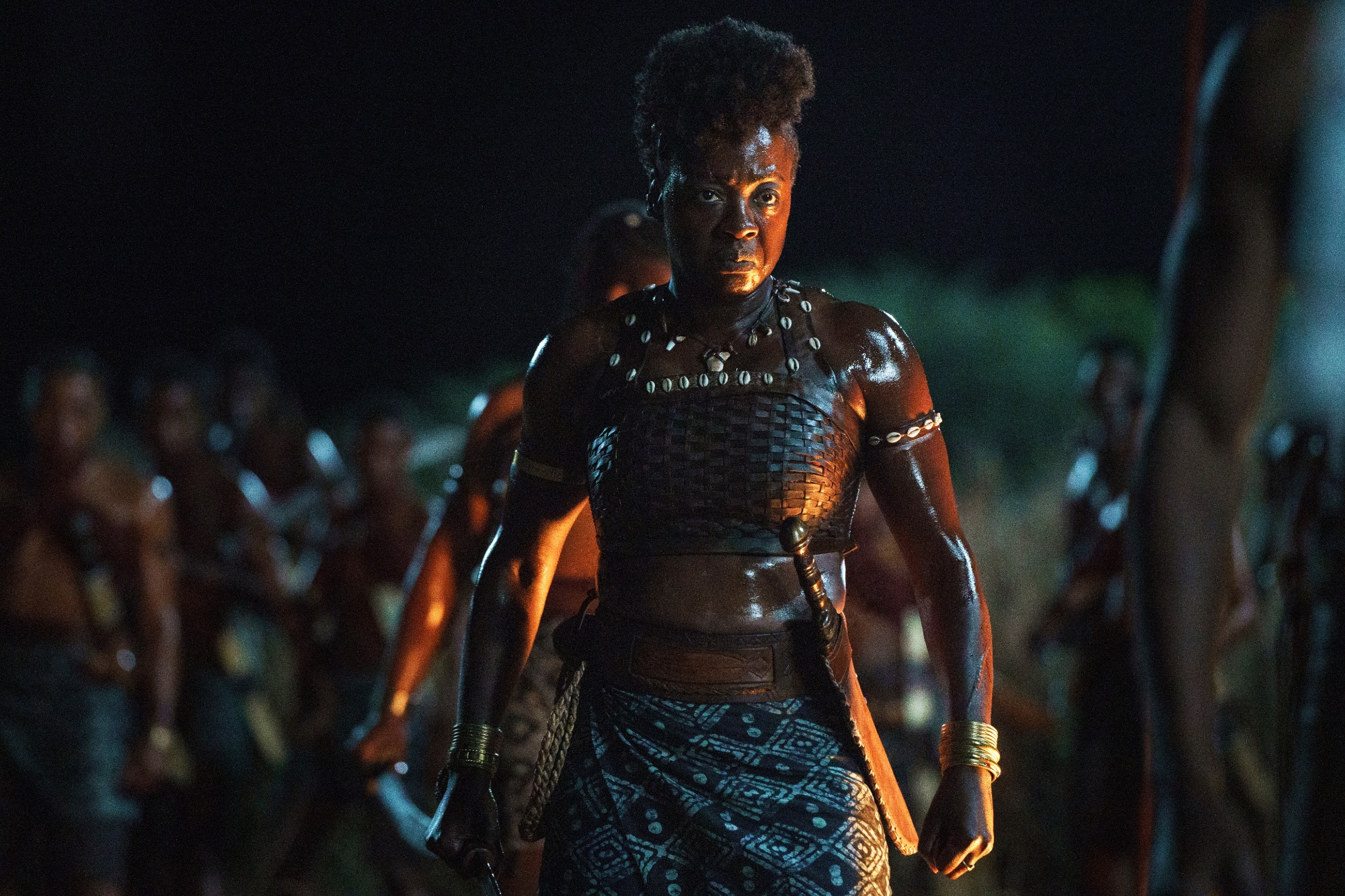 'The Woman King' Viola Davis as Nanisca looking serious wearing warrior clothes. Her warrior group stands behind her.
