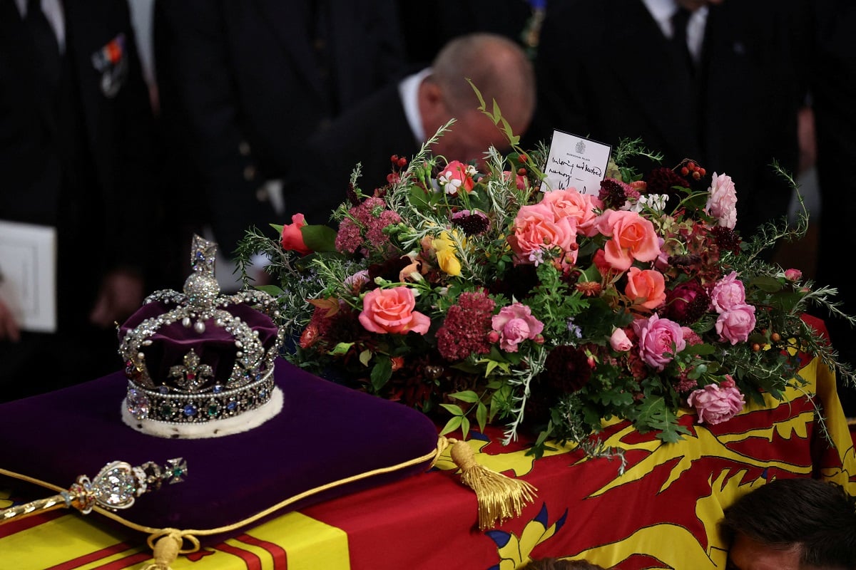 The coffin of Queen Elizabeth II, draped in the Royal Standard with the Imperial State Crown, flowers, and a card from Charles