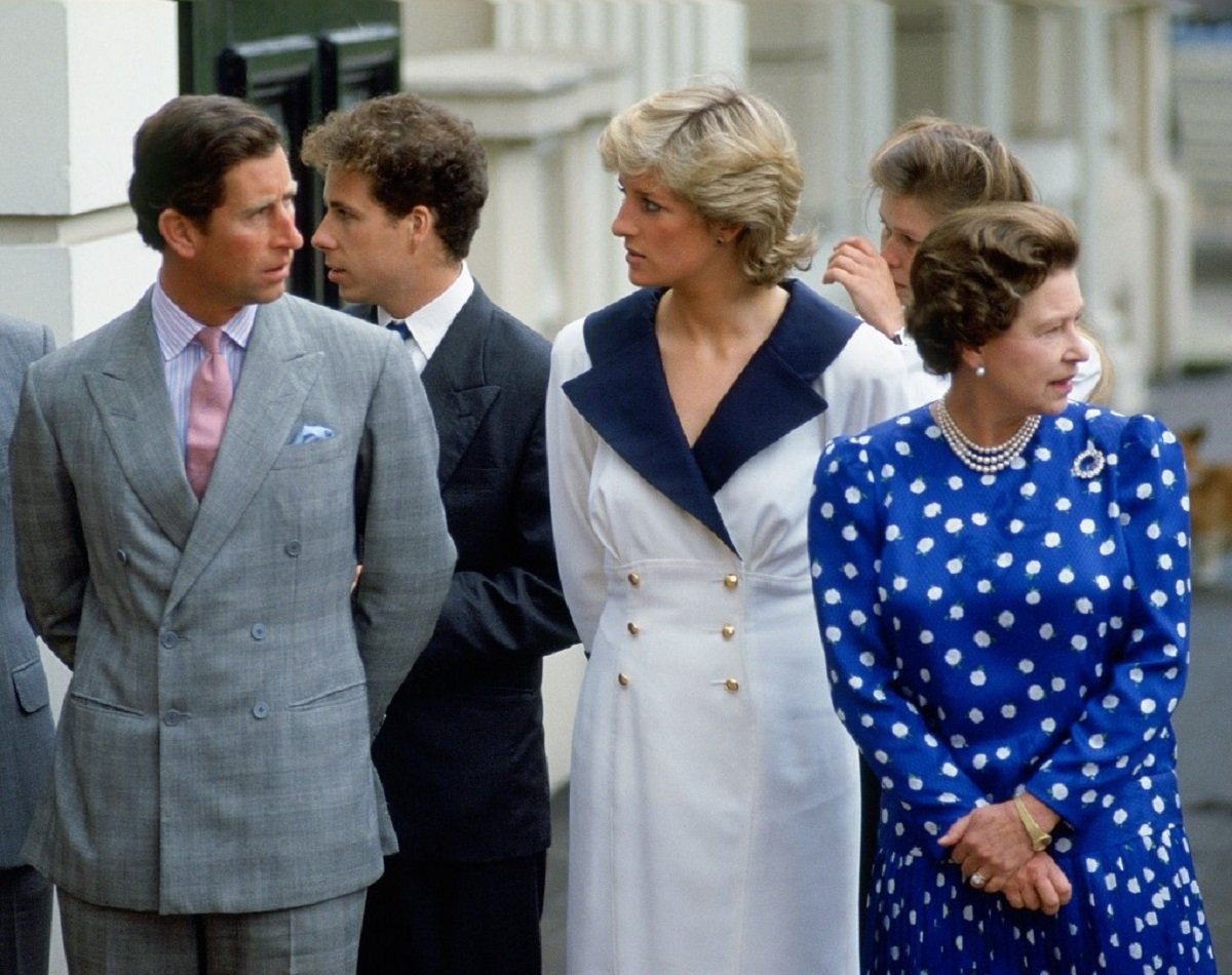 Then-Prince Charles and Princess Diana glaring at each other while standing next to Queen Elizabeth II